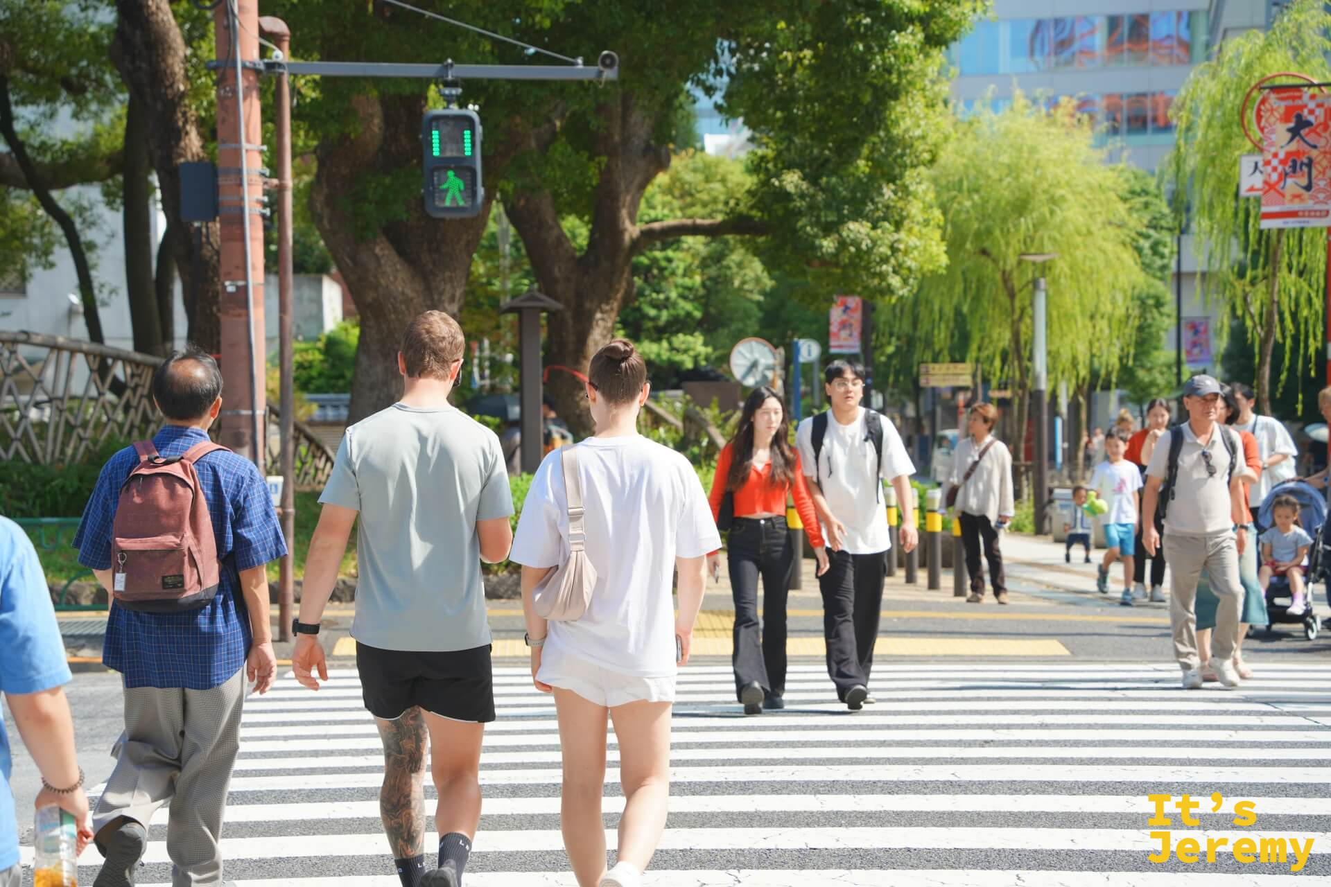 芝公園路口,人們走在開闊的人行道上,四周綠樹成蔭,東京的上午