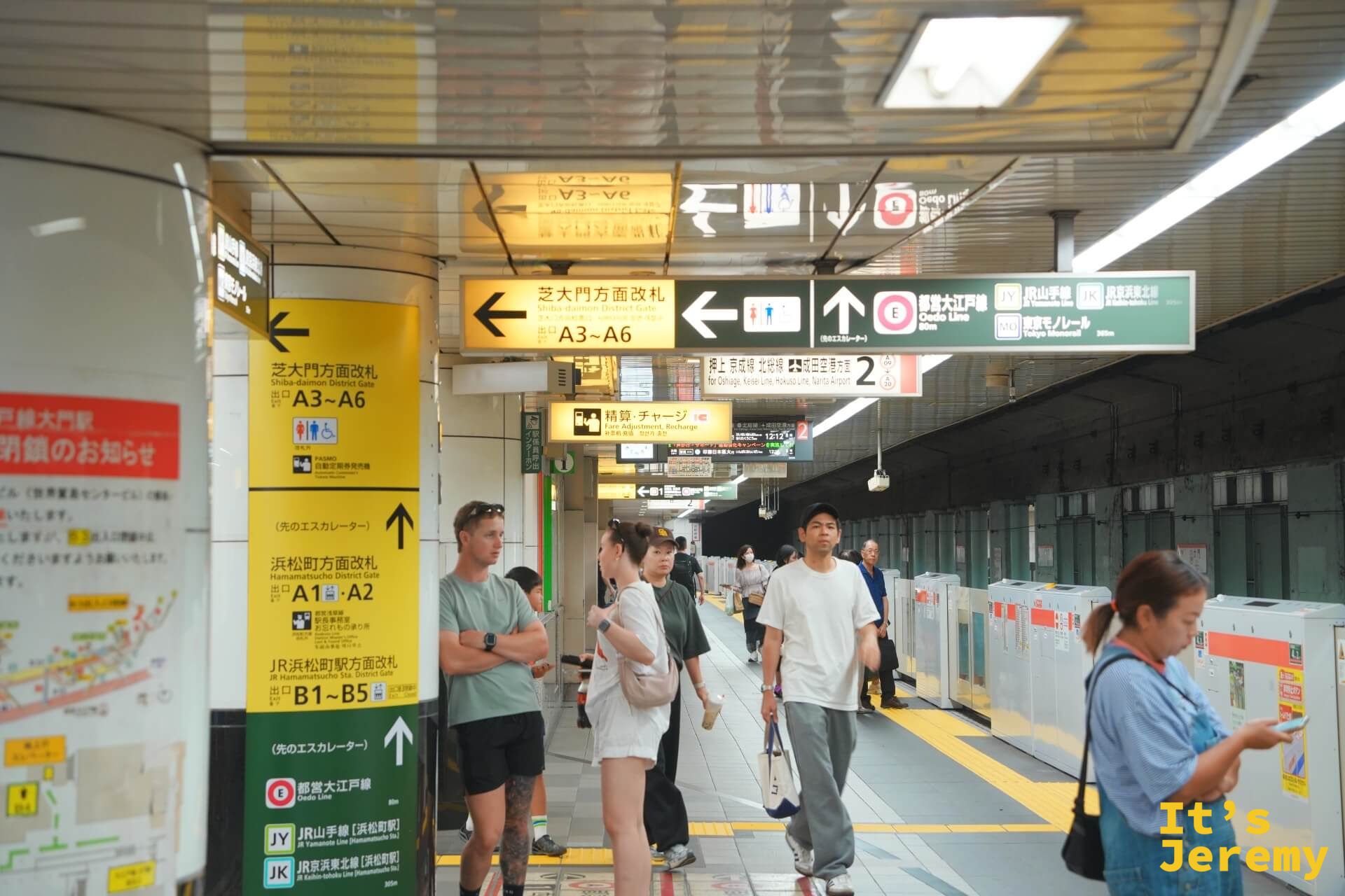 大門駅站內,黃色指示牌標示著「芝大門方面改札」「浜松町方面改札」,通勤客穿梭其間