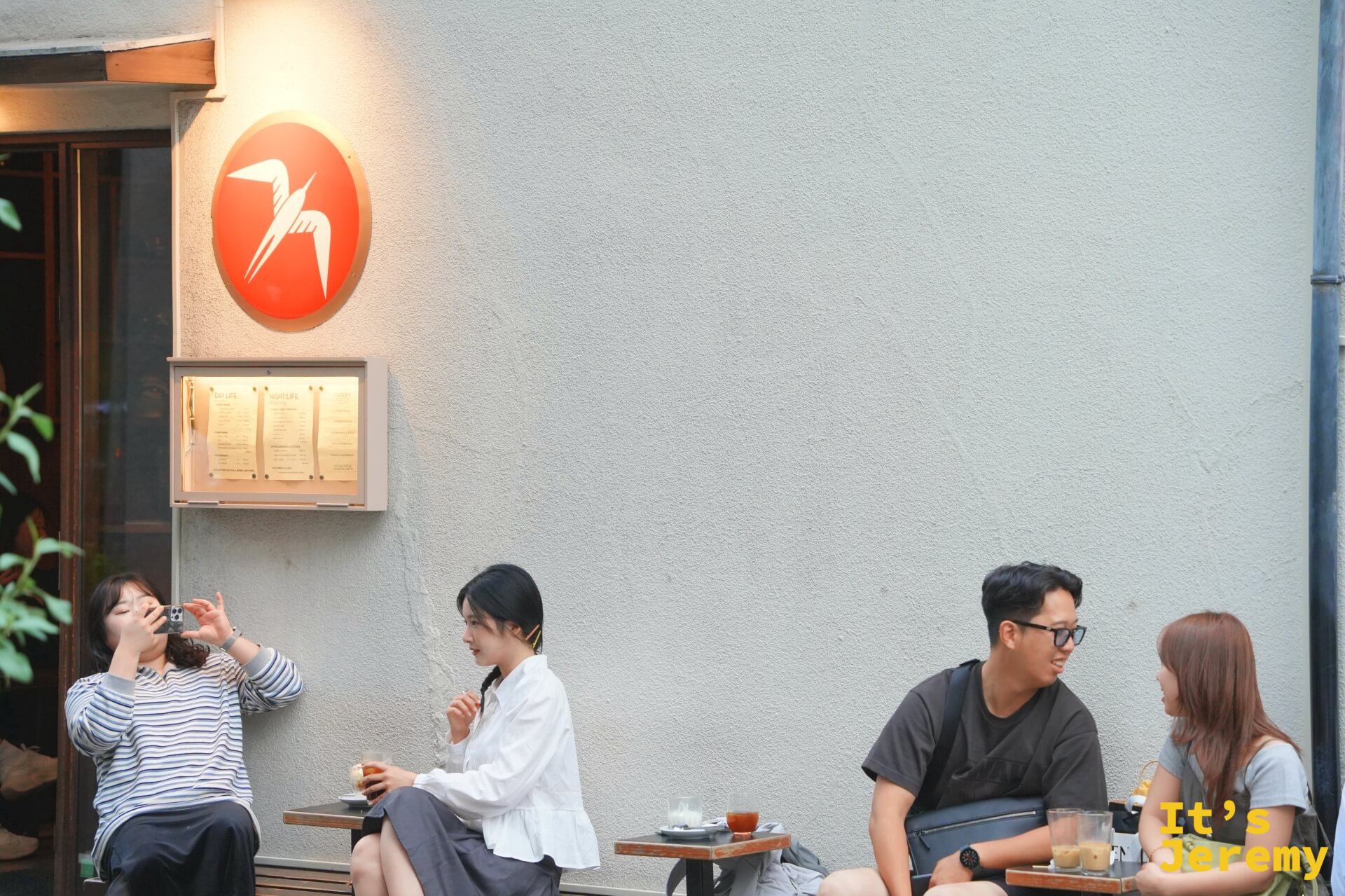 燕子 logo 圓牌近景,底下幾個客人各自發呆喝咖啡,午後的安靜節奏