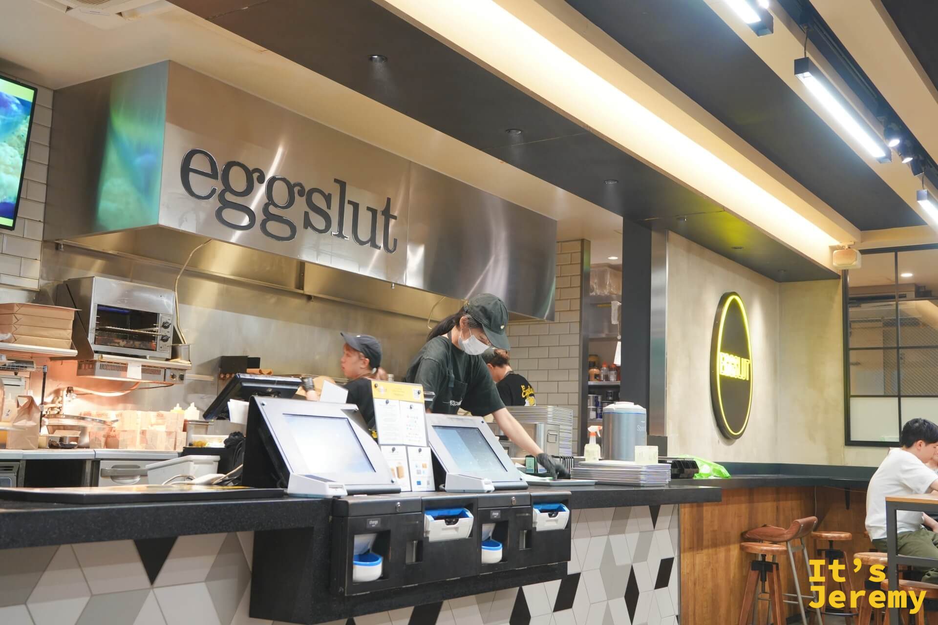 eggslut 店內廚房吧台，員工正在備料，eggslut 字樣在牆上