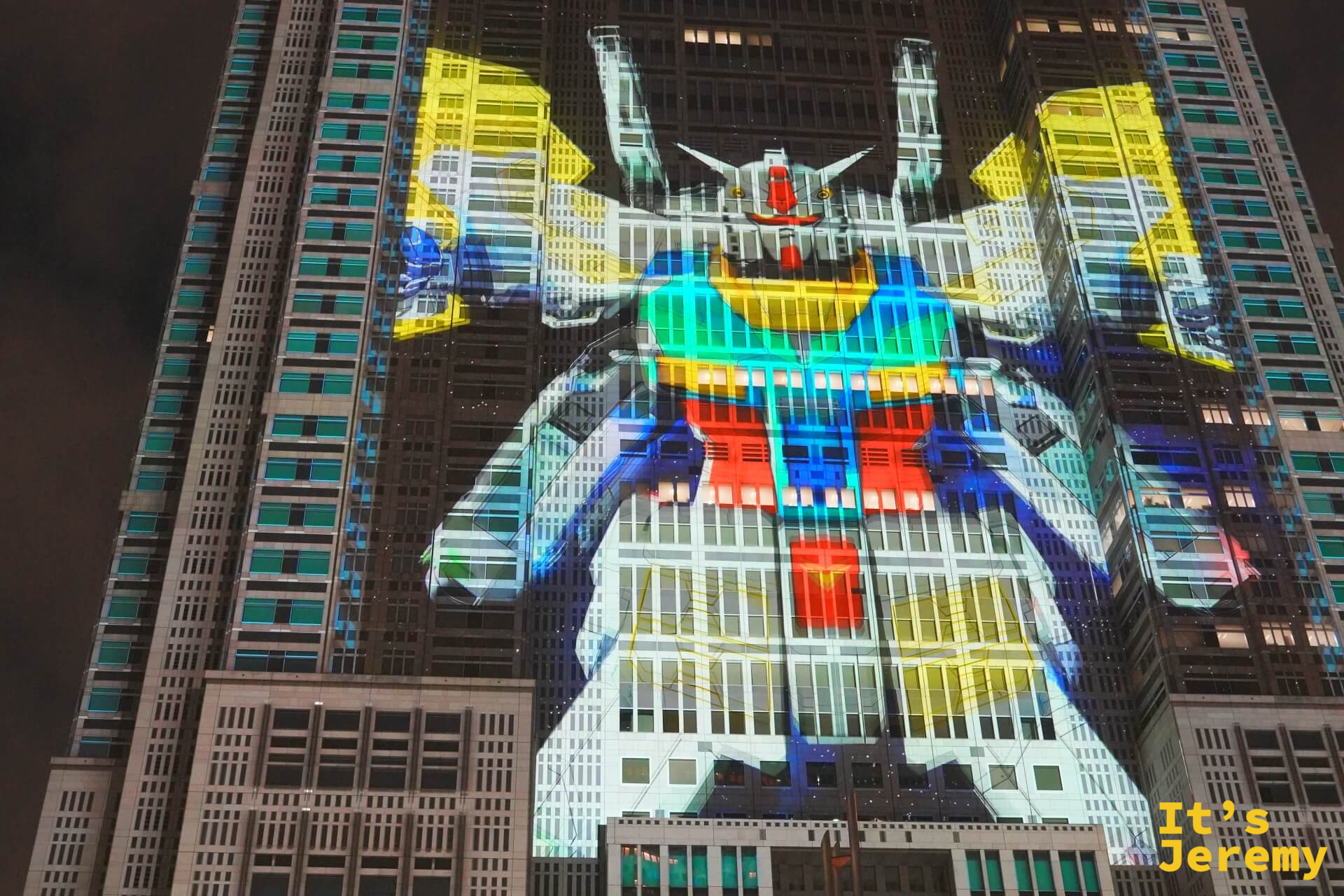 東京都廳外牆投影出鋼彈頭部與胸部特寫,黃藍紅白五色繽紛,充滿整棟大樓正面