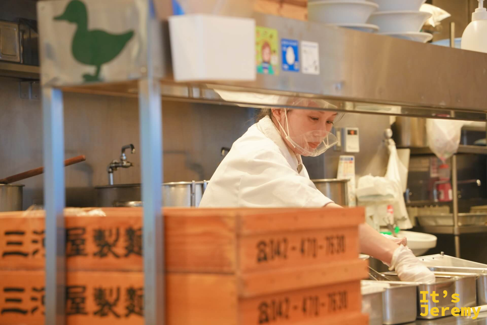 廚房工作人員認真備料的身影,後方疊著三屋製麵的木製麵箱