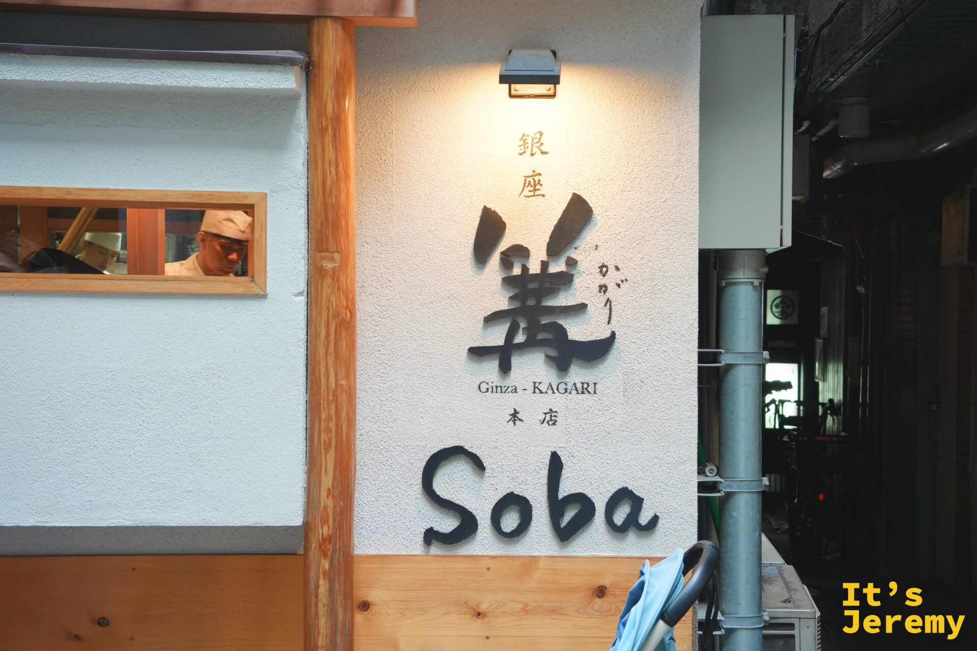門面外牆,「銀座 篝 Ginza-KAGARI 本店 Soba」字樣清晰,廚師透過小窗隱約可見