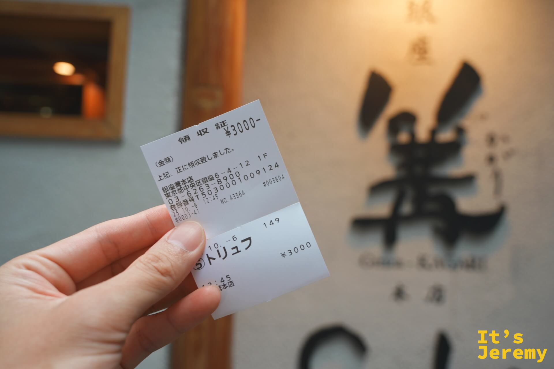 手持餐券,上方標注¥3000與「トリュフ」,背景是店家外牆