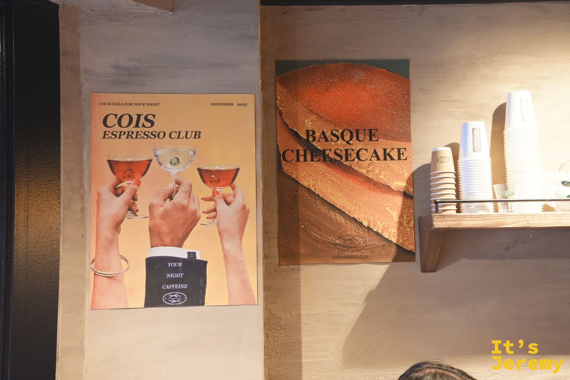 店內牆面的 Cois Espresso Club 調酒海報與巴斯克起司蛋糕海報並排,是這家店日咖夜酒概念最直白的宣示