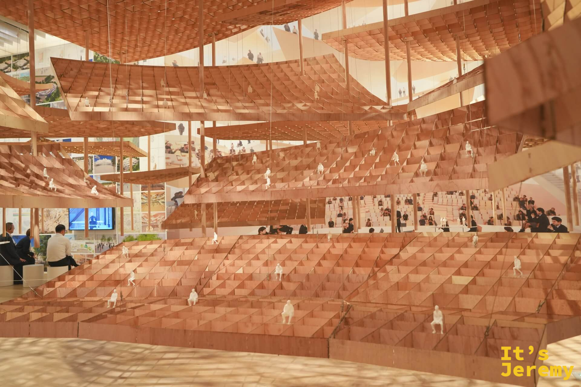 懸掛式大型建築模型全景，呈現多層梯狀斜面，白色人物散落其中