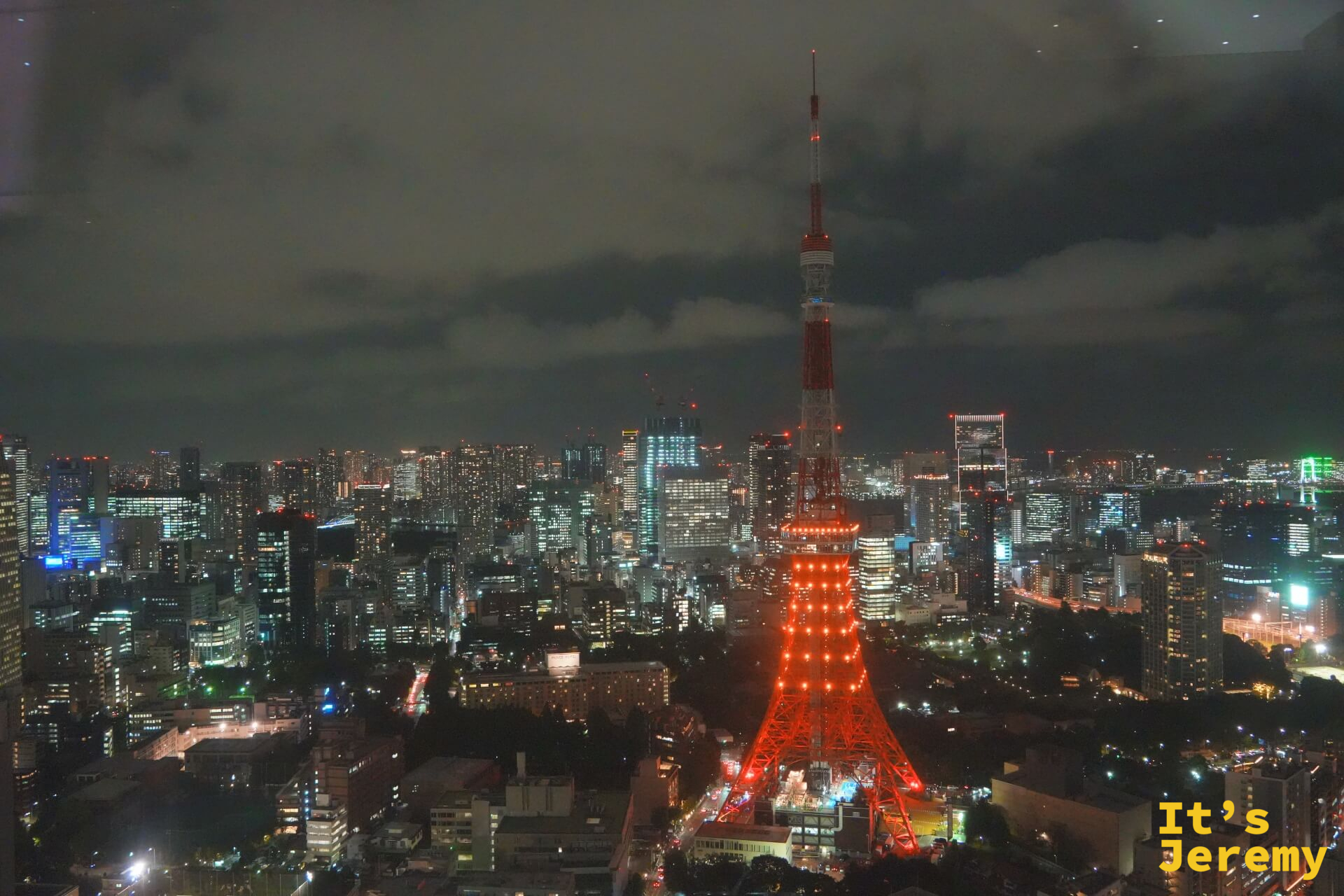 從麻布台之丘高樓俯瞰,東京鐵塔橘紅色燈光照亮下半段,上半部沒有亮燈,尖端沒入夜色