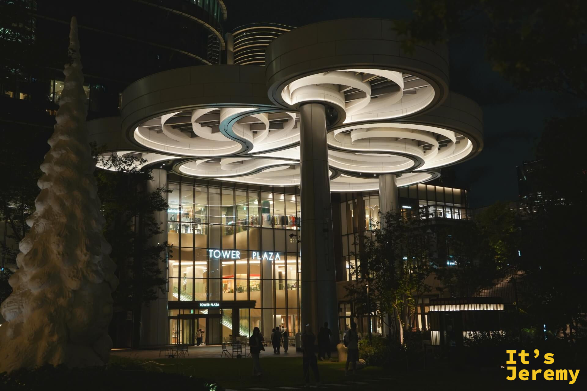 麻布台之丘 Tower Plaza 夜間外觀,入口上方的蘑菇形白色發光燈柱向外延伸,建築線條圓潤有機