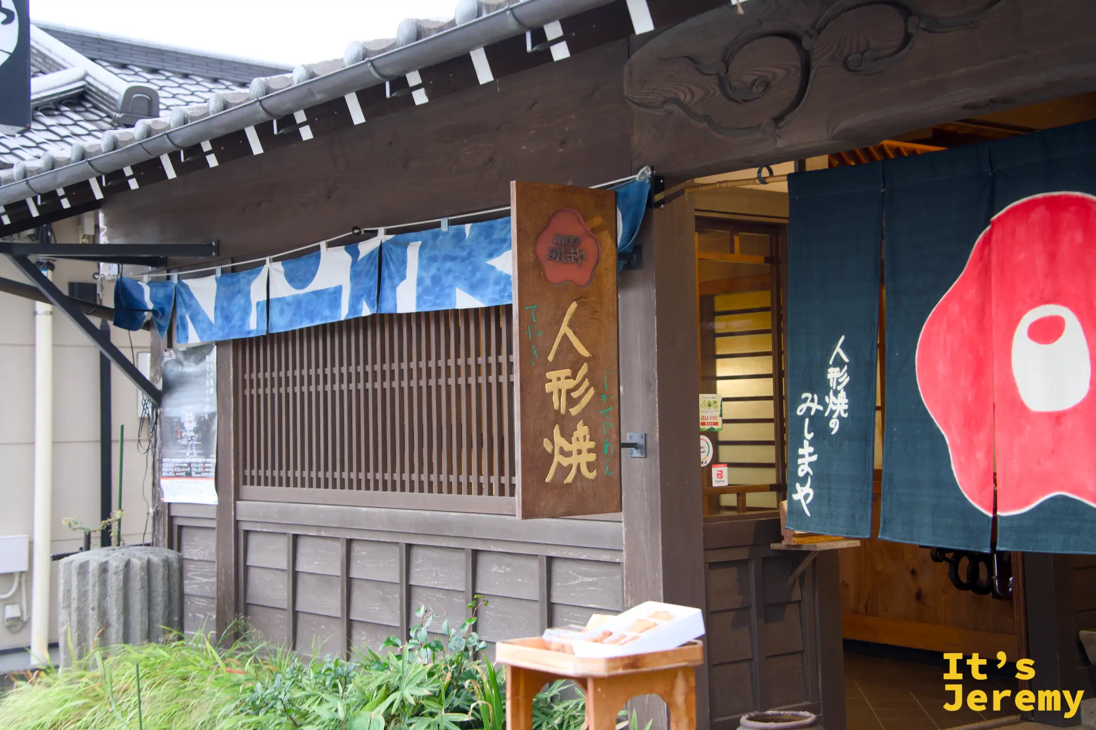 人形焼みしまや 店招特寫，木製招牌「人形焼 みしまや」，旁邊藍底橘圓暖簾