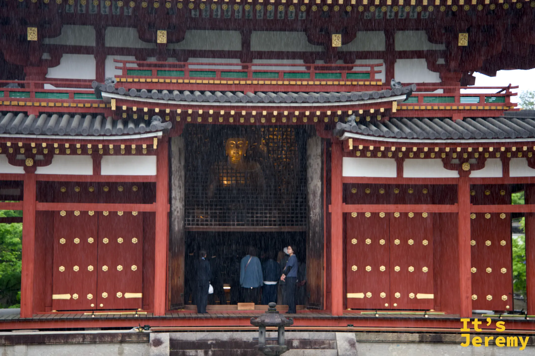 重雨中的鳳凰堂正門，隱約可見堂內阿彌陀如來坐像的金色身影