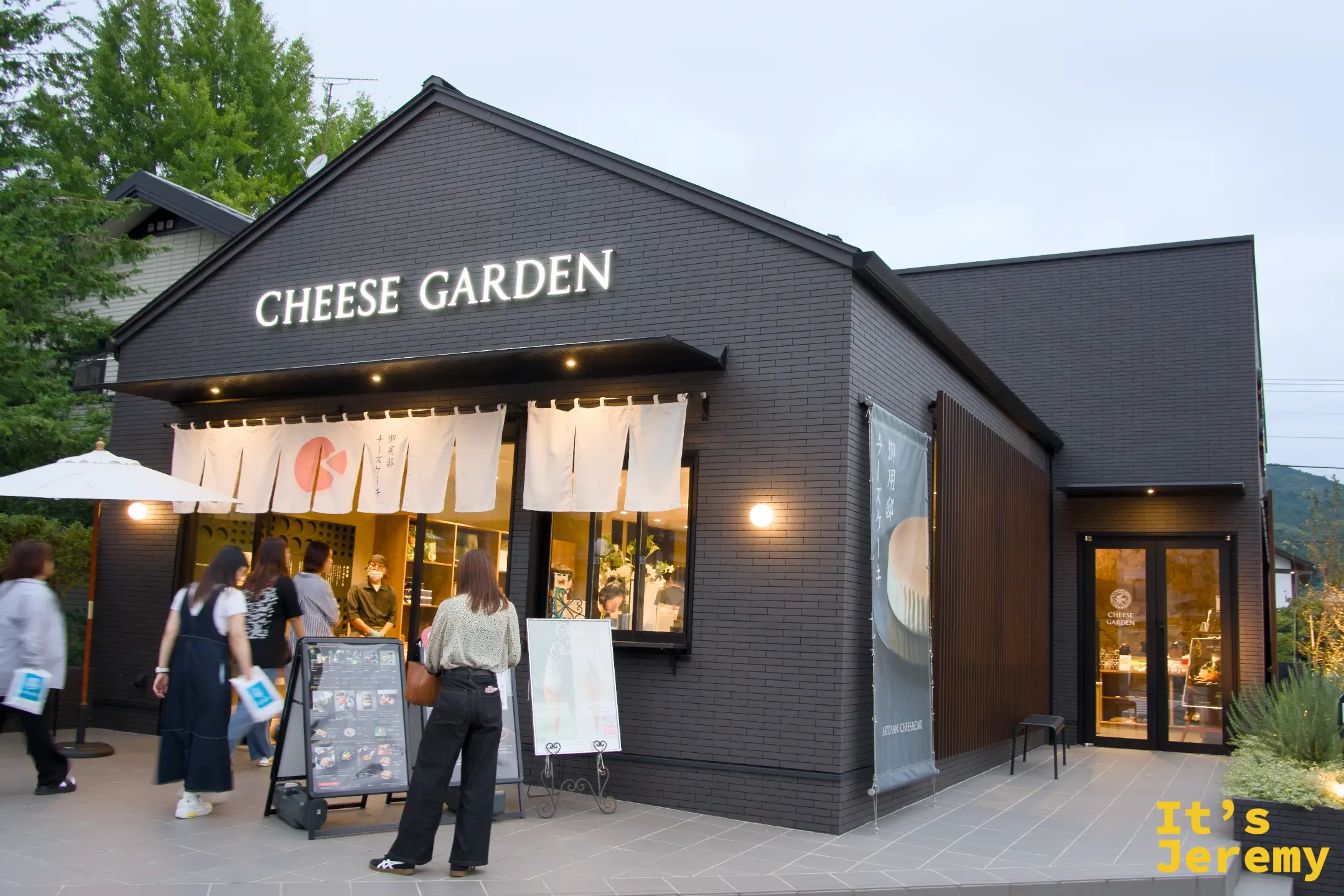 CHEESE GARDEN 外觀，深灰黑磚建築，白色招牌，傍晚有遊客在門口