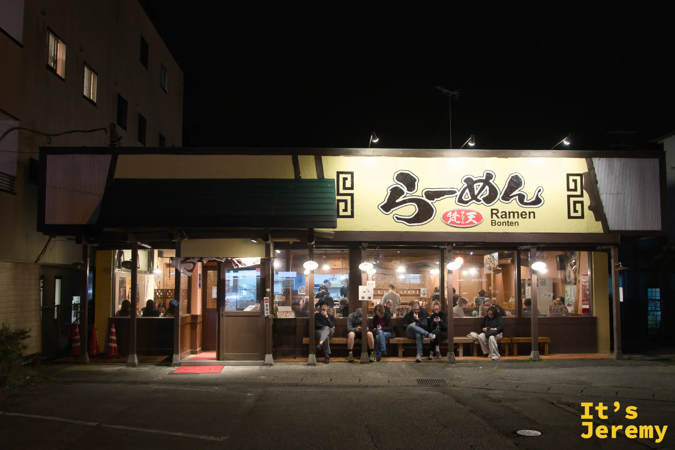 らーめん梵天夜拍全景，整棟建築正面在夜色中，招牌燈光溫暖，店外依然有旅人等位