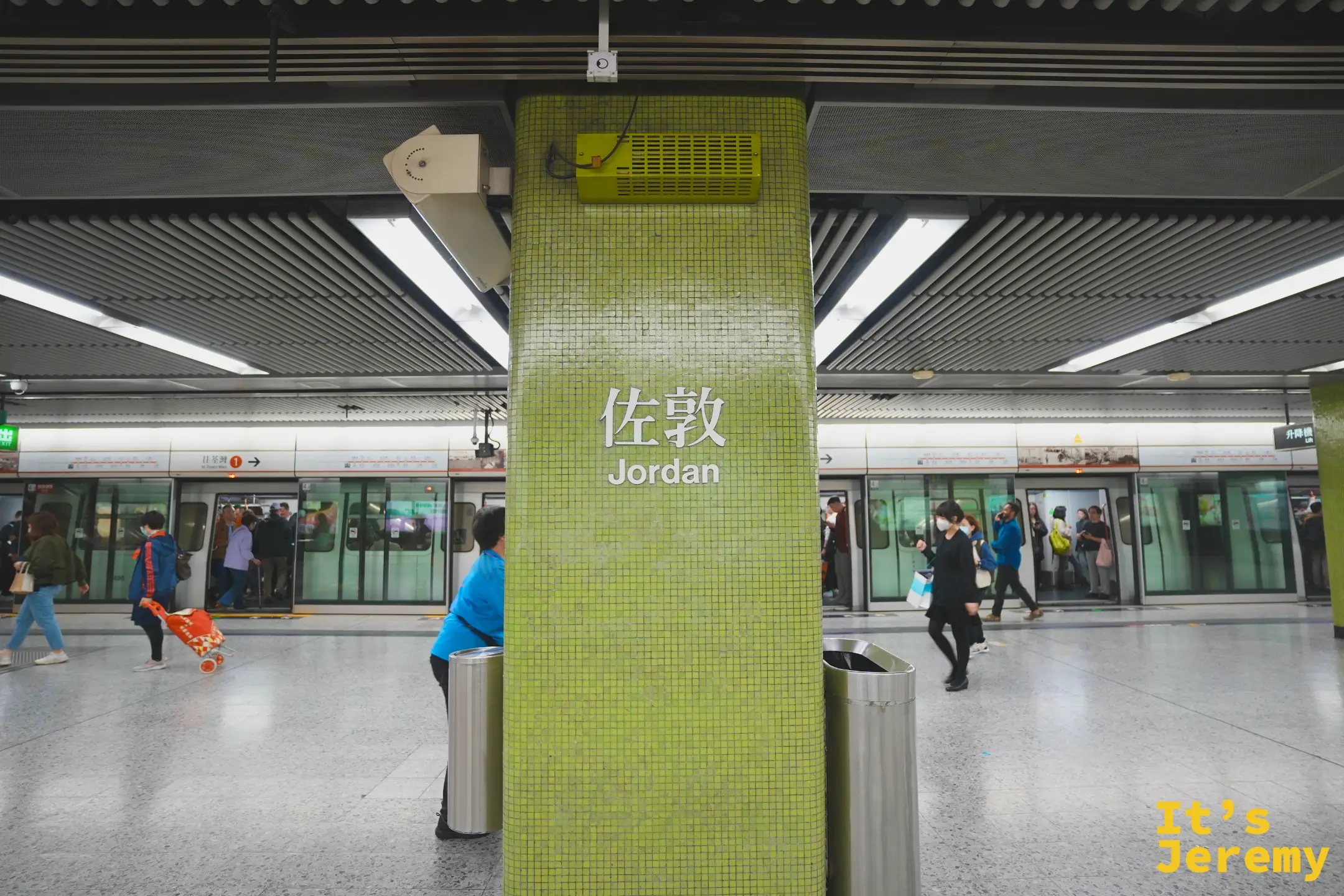 港鐵佐敦站月台，抹茶綠磁磚柱上寫著「佐敦 Jordan」，兩側停著列車、旅客往來
