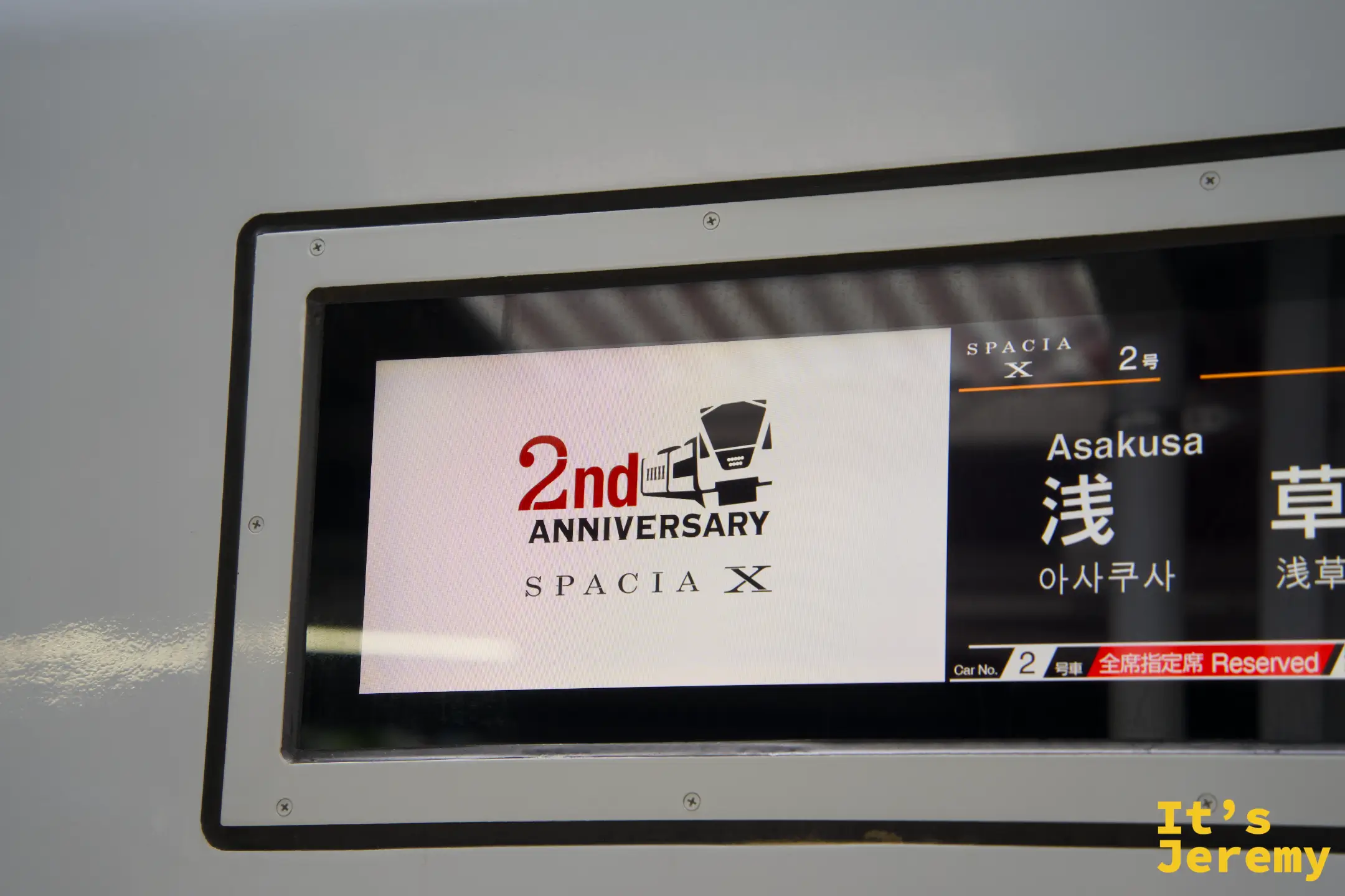 車廂顯示螢幕，左側貼有「2nd Anniversary SPACIA X」慶祝貼紙，右側顯示「Asakusa 浅草」目的地及「全席指定席 Reserved」