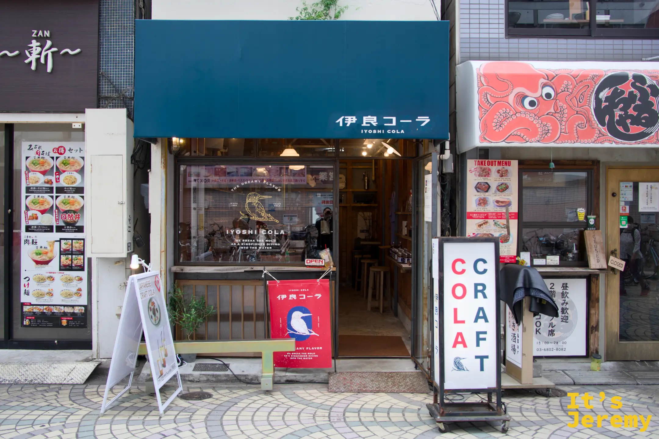 浅草六区店面外觀，青藍色遮陽棚與 COLA CRAFT 立牌