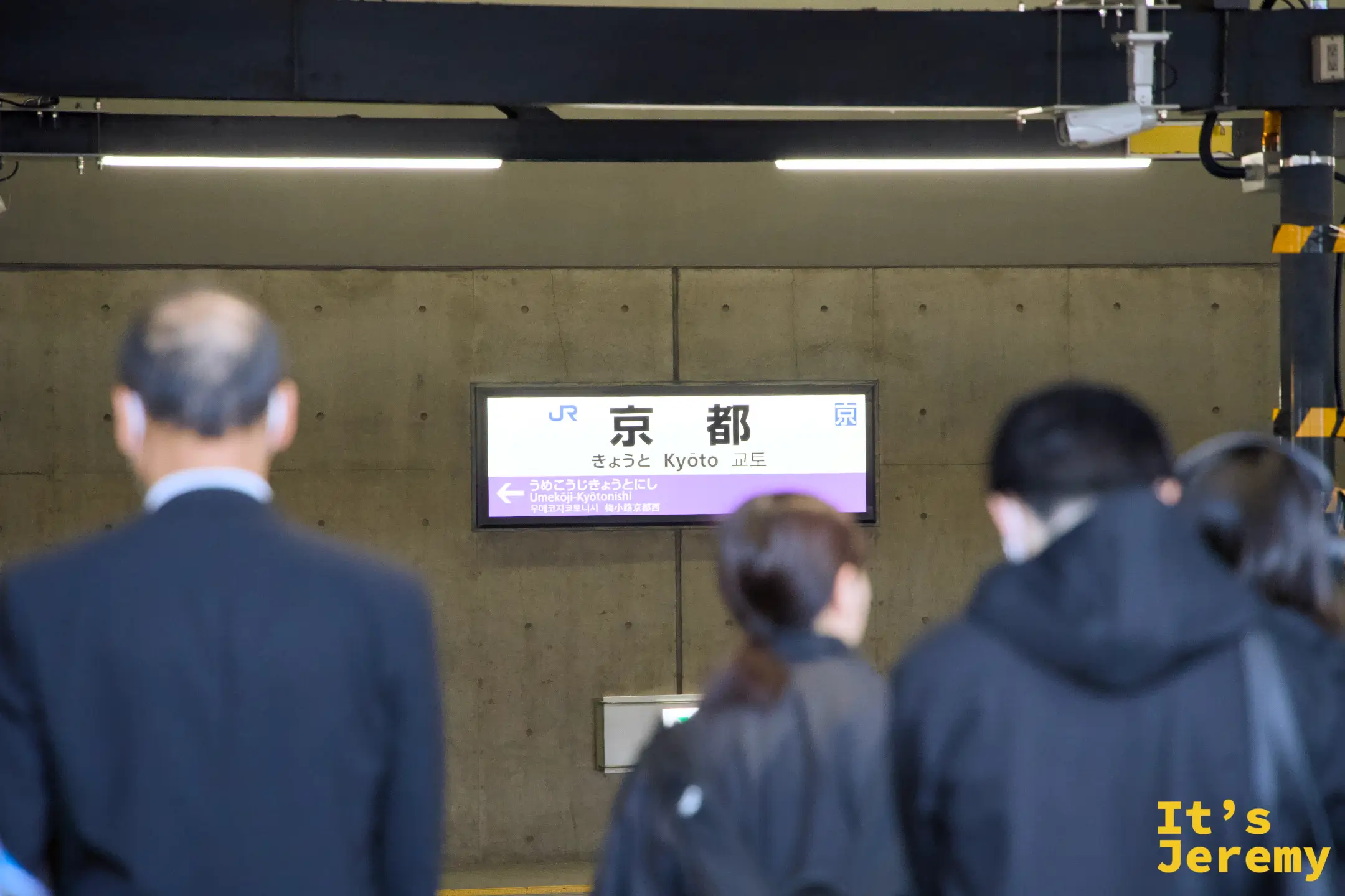 JR京都駅の駅名標と旅客の後ろ姿