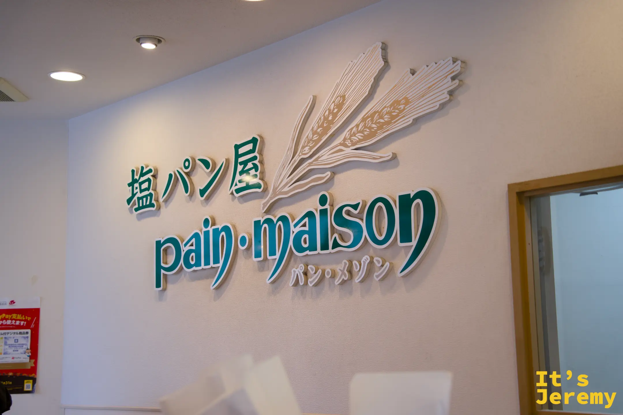 店內牆面招牌，「塩パン屋 pain·maison」綠色字體