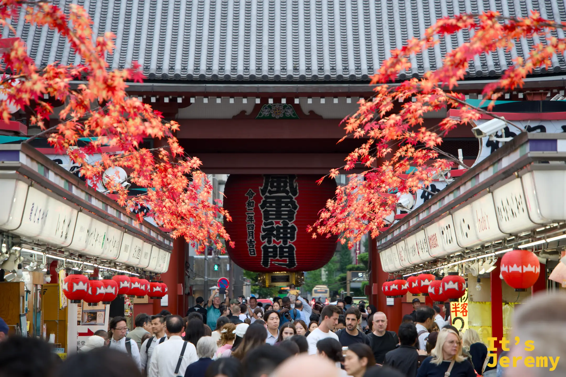 從仲見世通り內回望雷門，秋日橘紅燈籠排列兩側，「風雷神門」大燈籠懸於入口