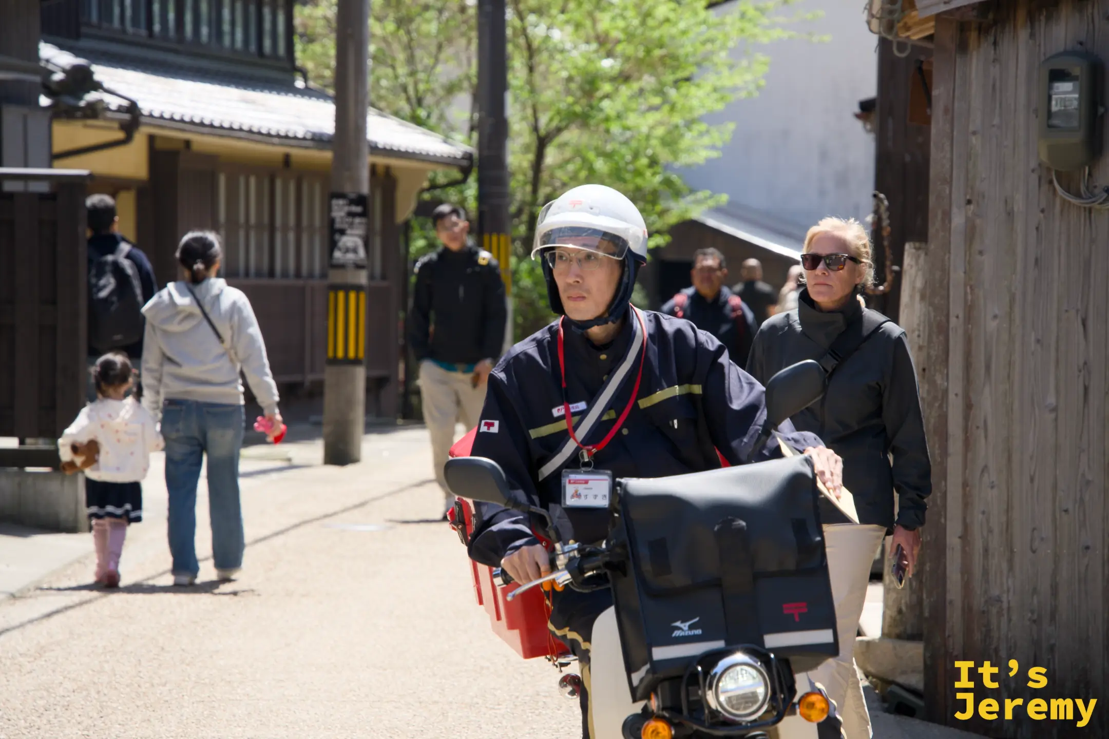 郵便配達員が伊根の路地をバイクで走る
