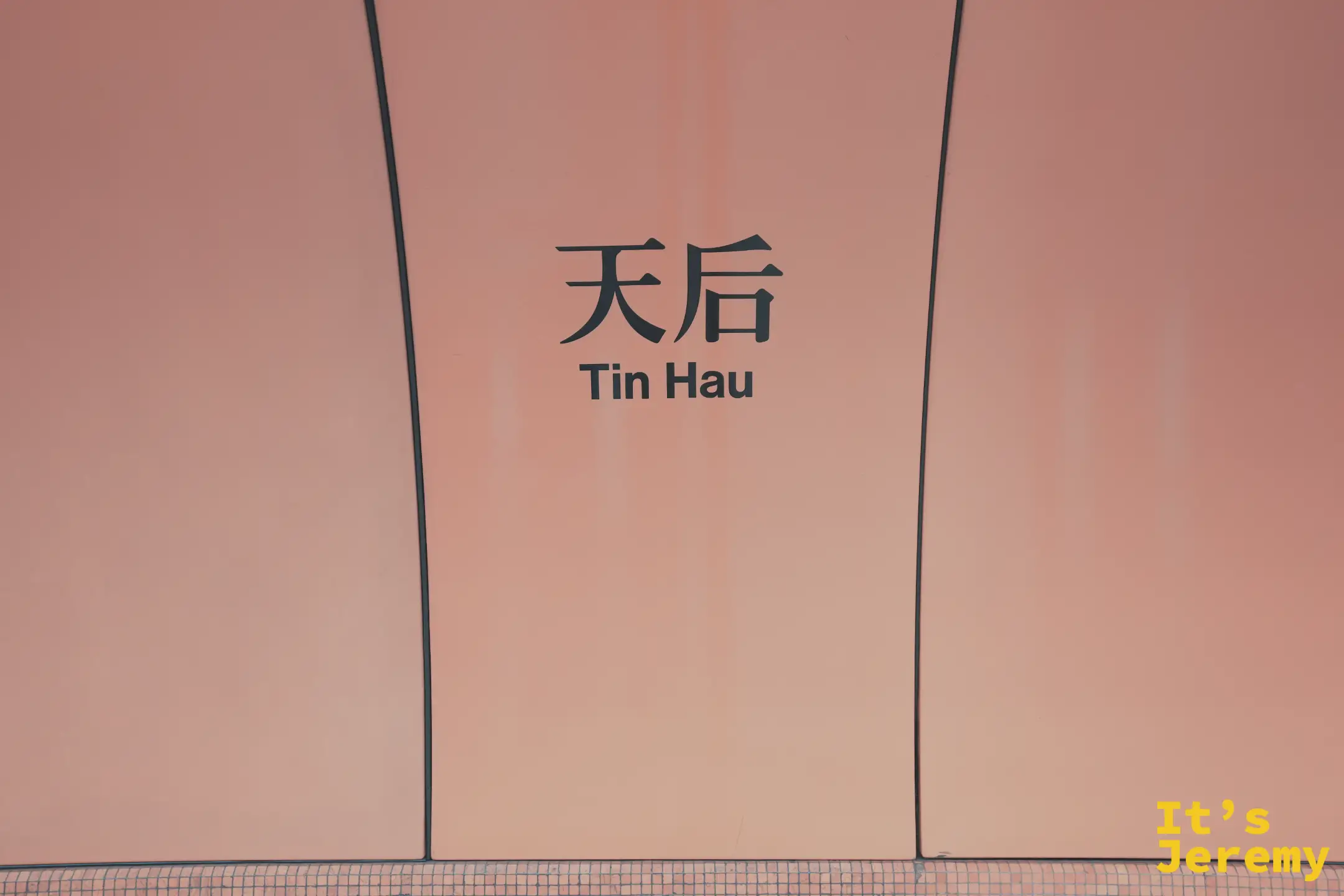 港鐵天后站的橘色牆面，黑字寫著「天后 Tin Hau」