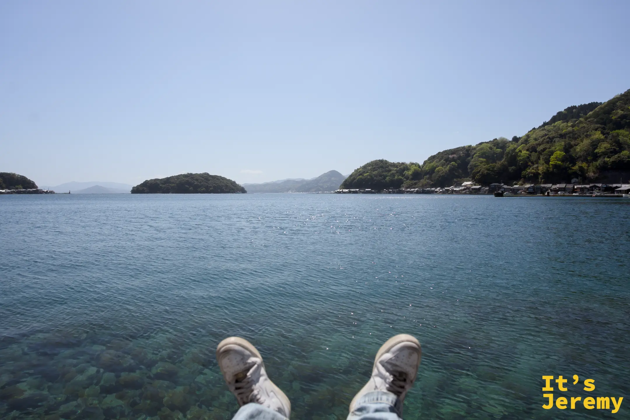 伊根湾に足を投げ出して座る