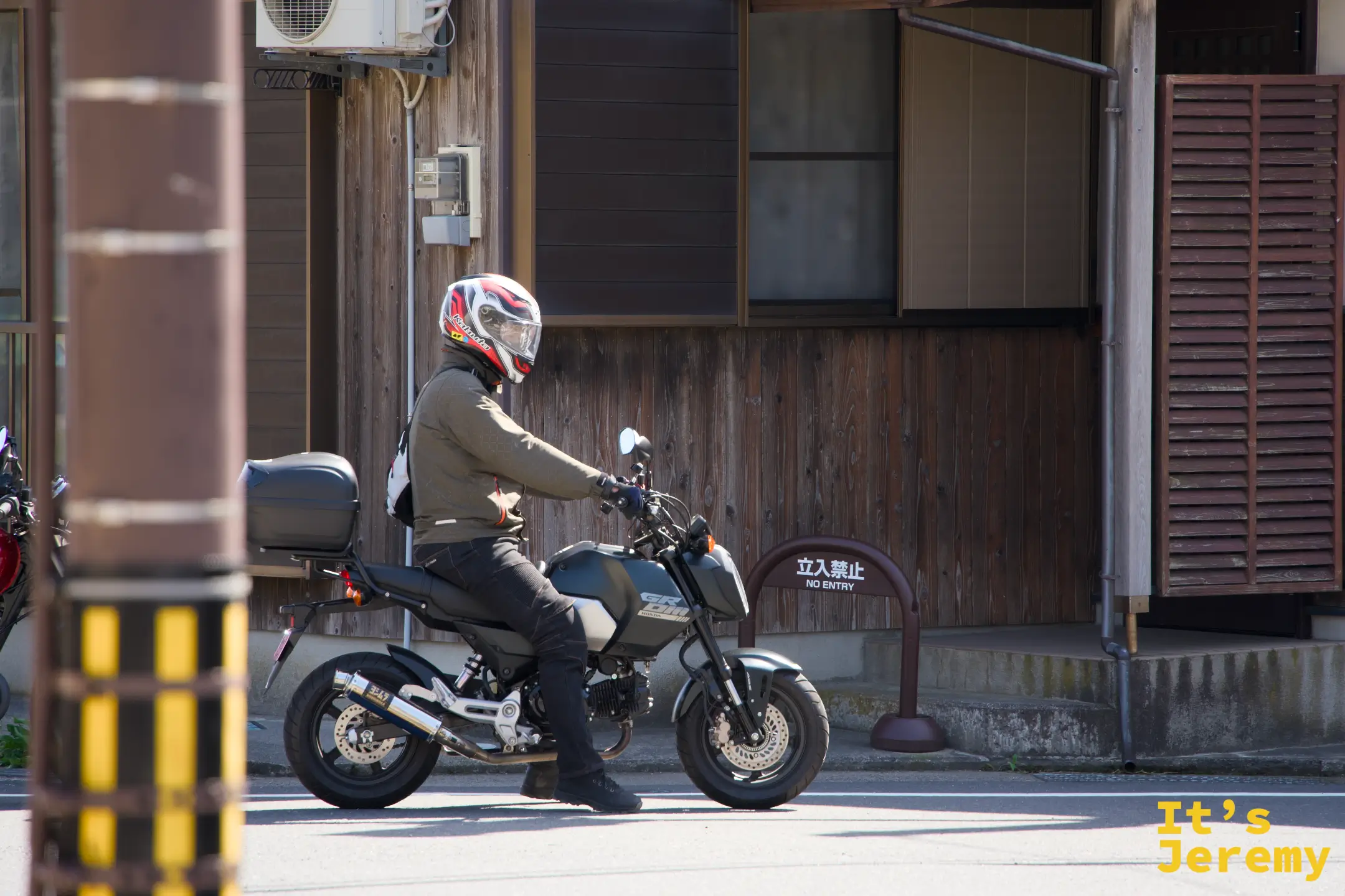 伊根の舟屋の前をバイクが走る