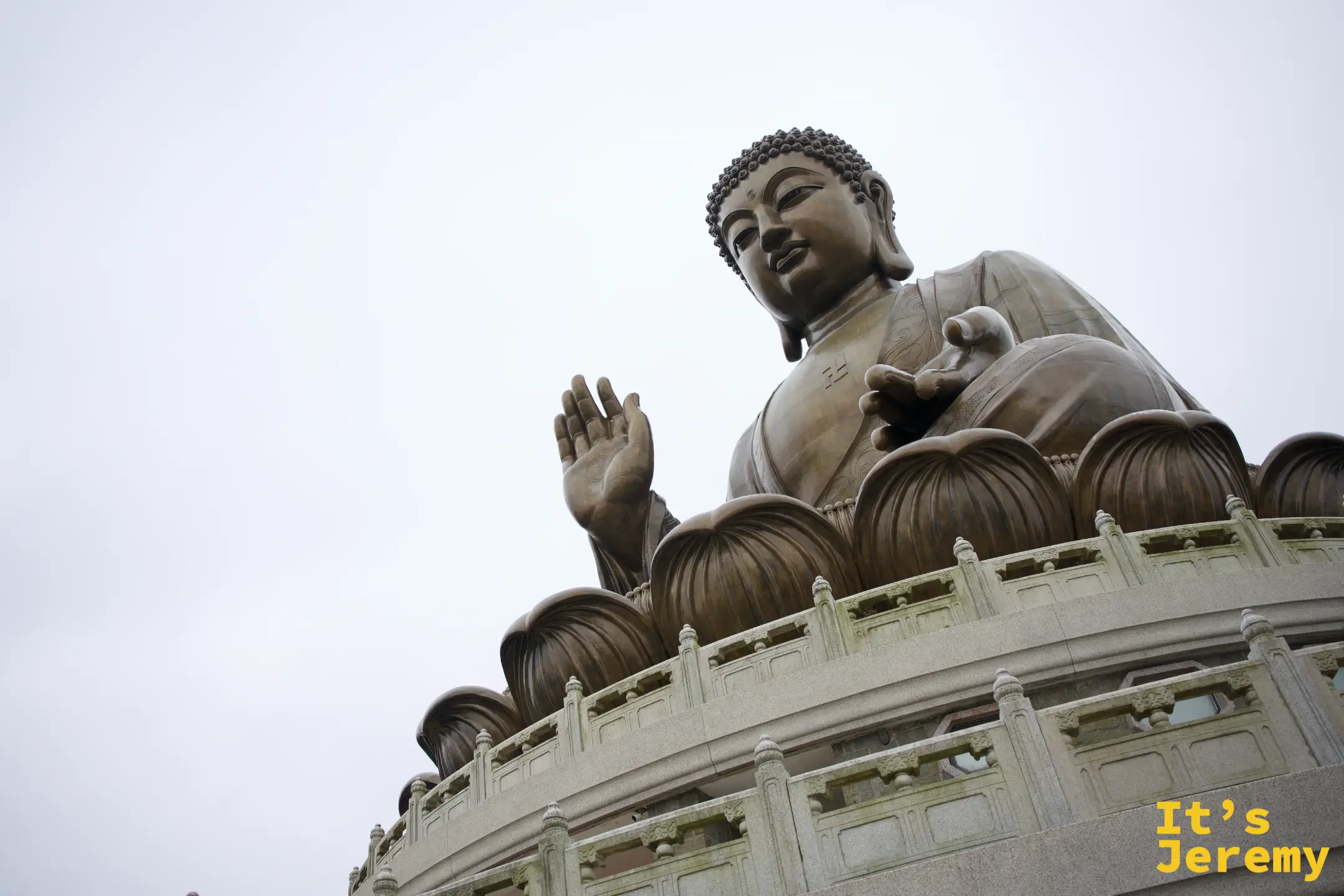從側下方仰望天壇大佛全身，右手施無畏印、左手結印置於膝上，端坐在青銅蓮花座上，胸前卍字清晰