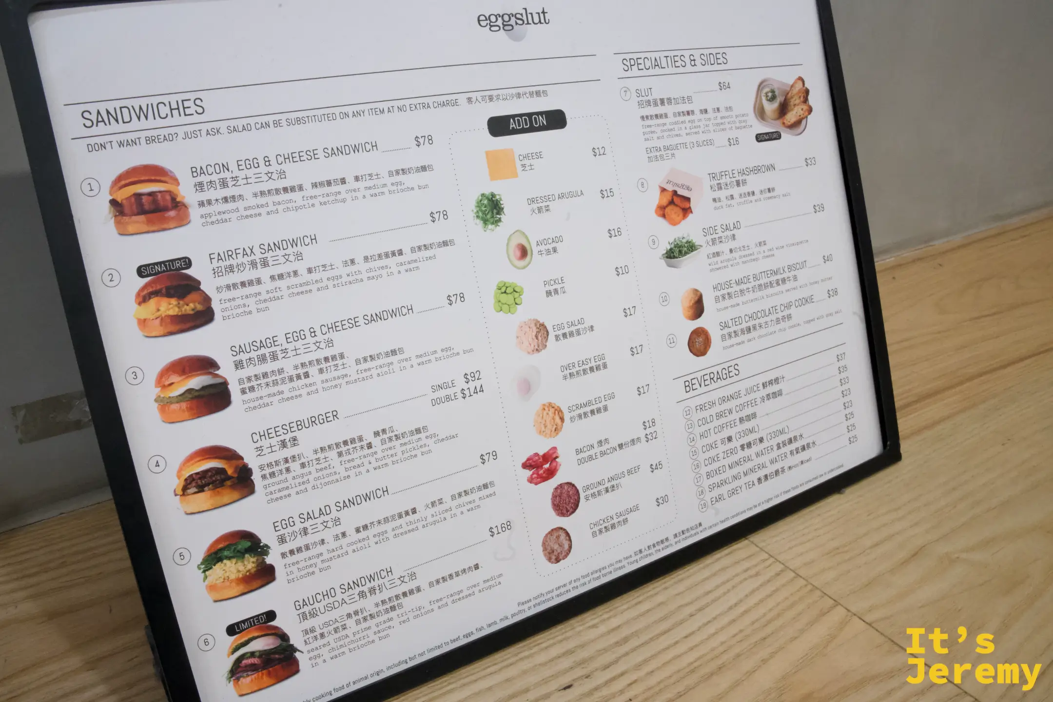 eggslut 立式菜單板，列出 Bacon Egg & Cheese、Fairfax Sandwich、Sausage Egg & Cheese 等三明治與 Slut、薯餅等副餐及飲料，附中英文與價格