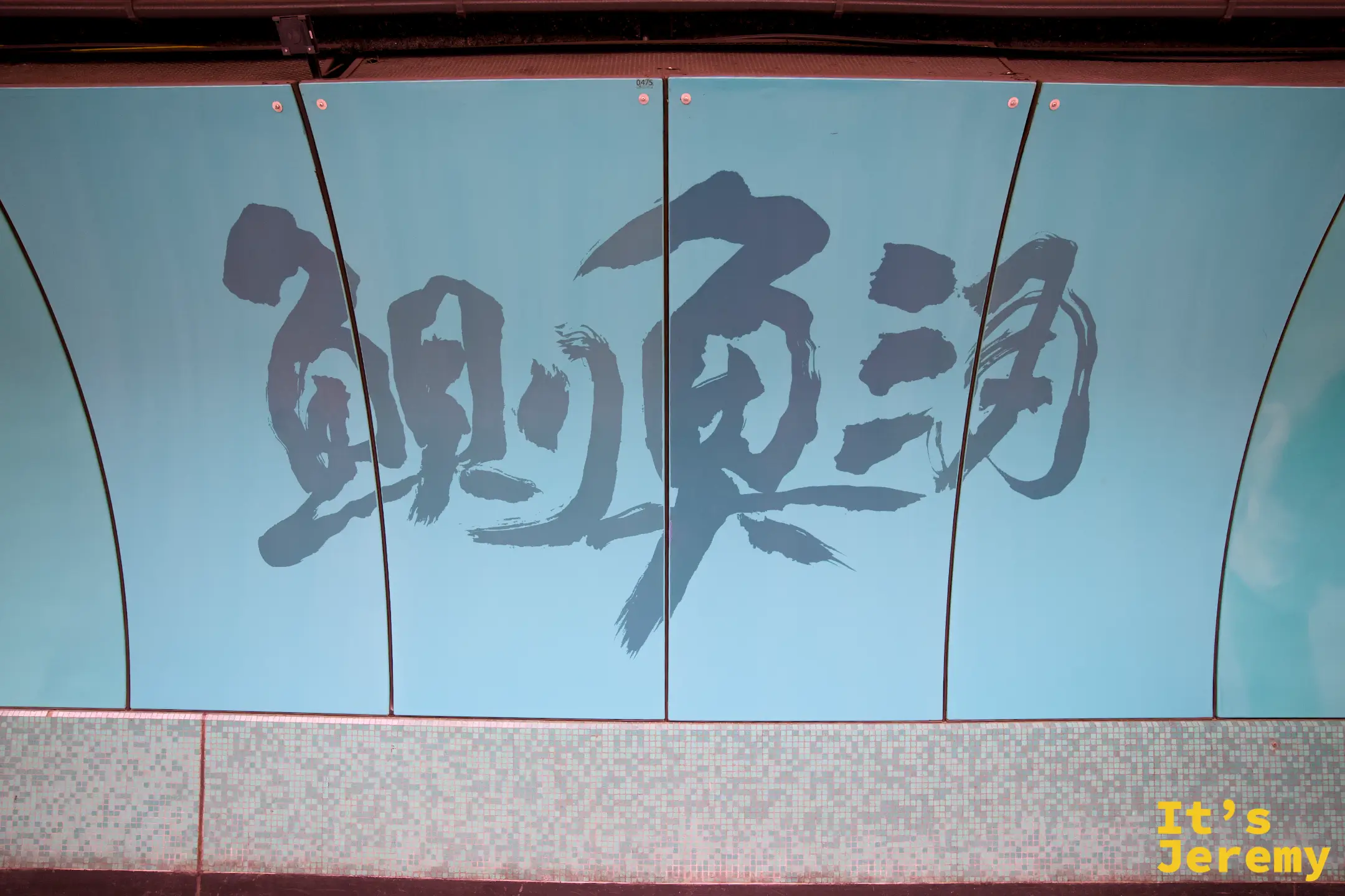 鰂魚涌站月台牆上以綠色書法寫著站名「鰂魚涌」