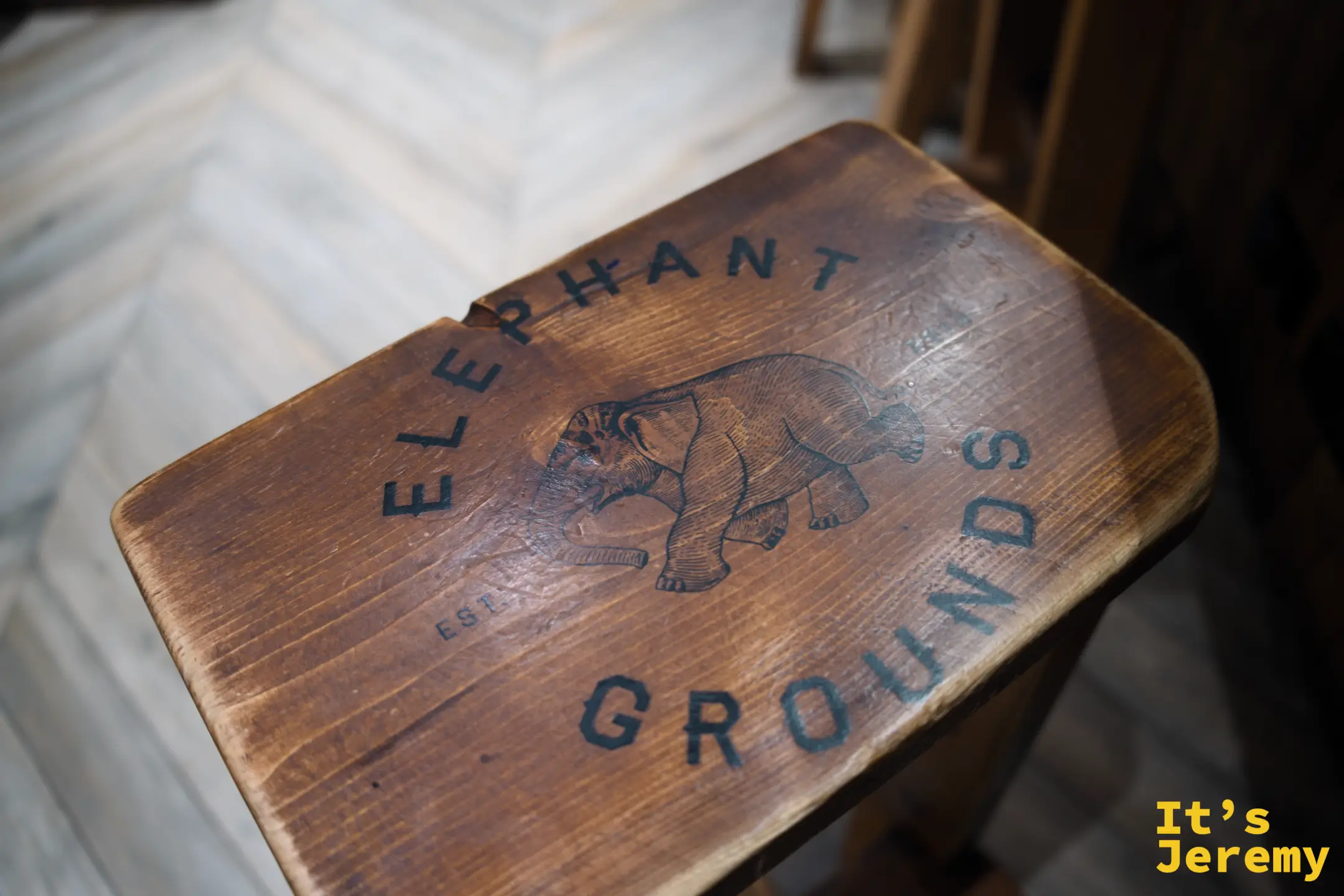 木凳椅面上烙印著 Elephant Grounds 的大象 logo 與店名