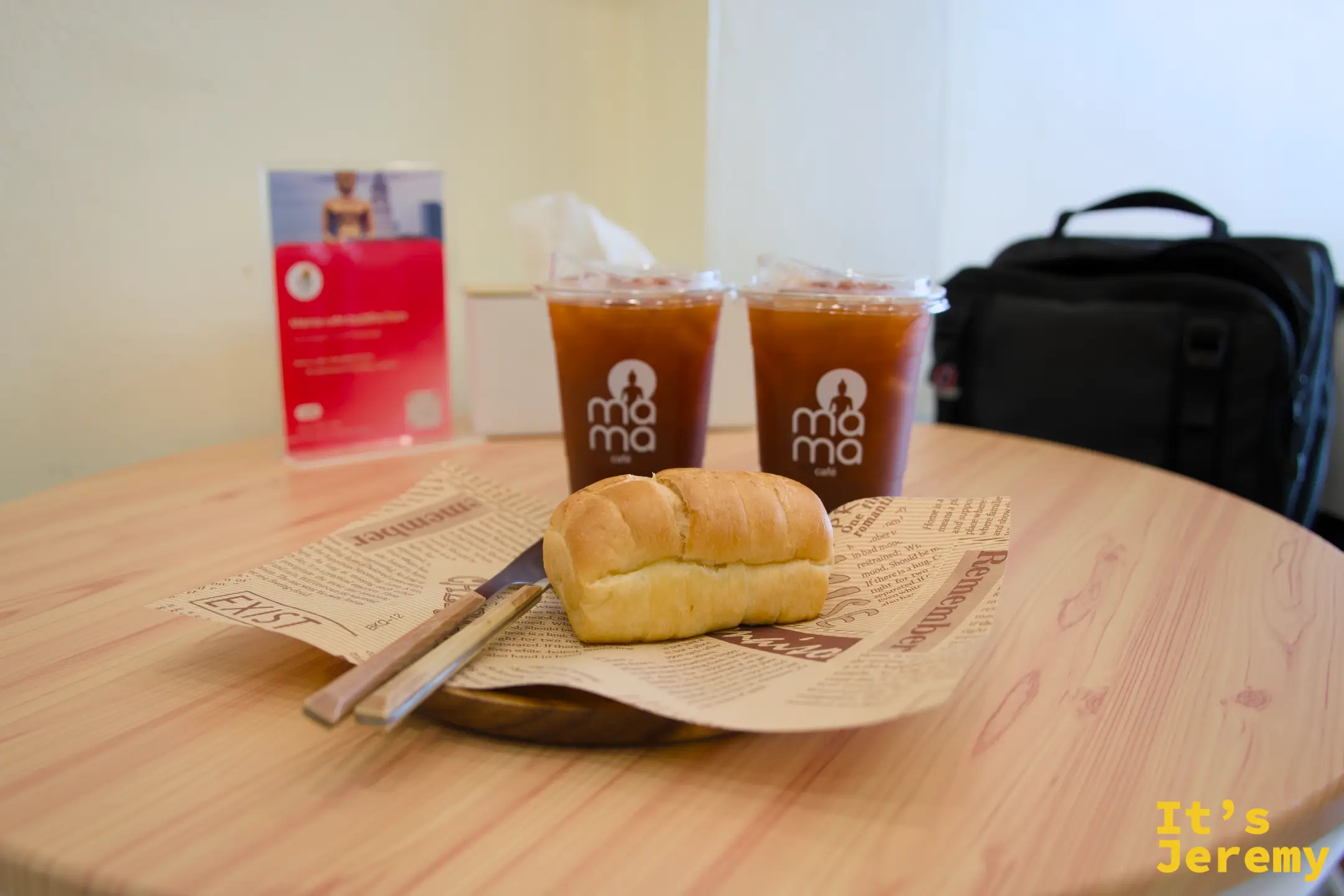 「MAMA CAFE」店內的木桌上擺放著兩杯冰咖啡與一份現烤鹽麵包，呈現愜意的午後點心時光。