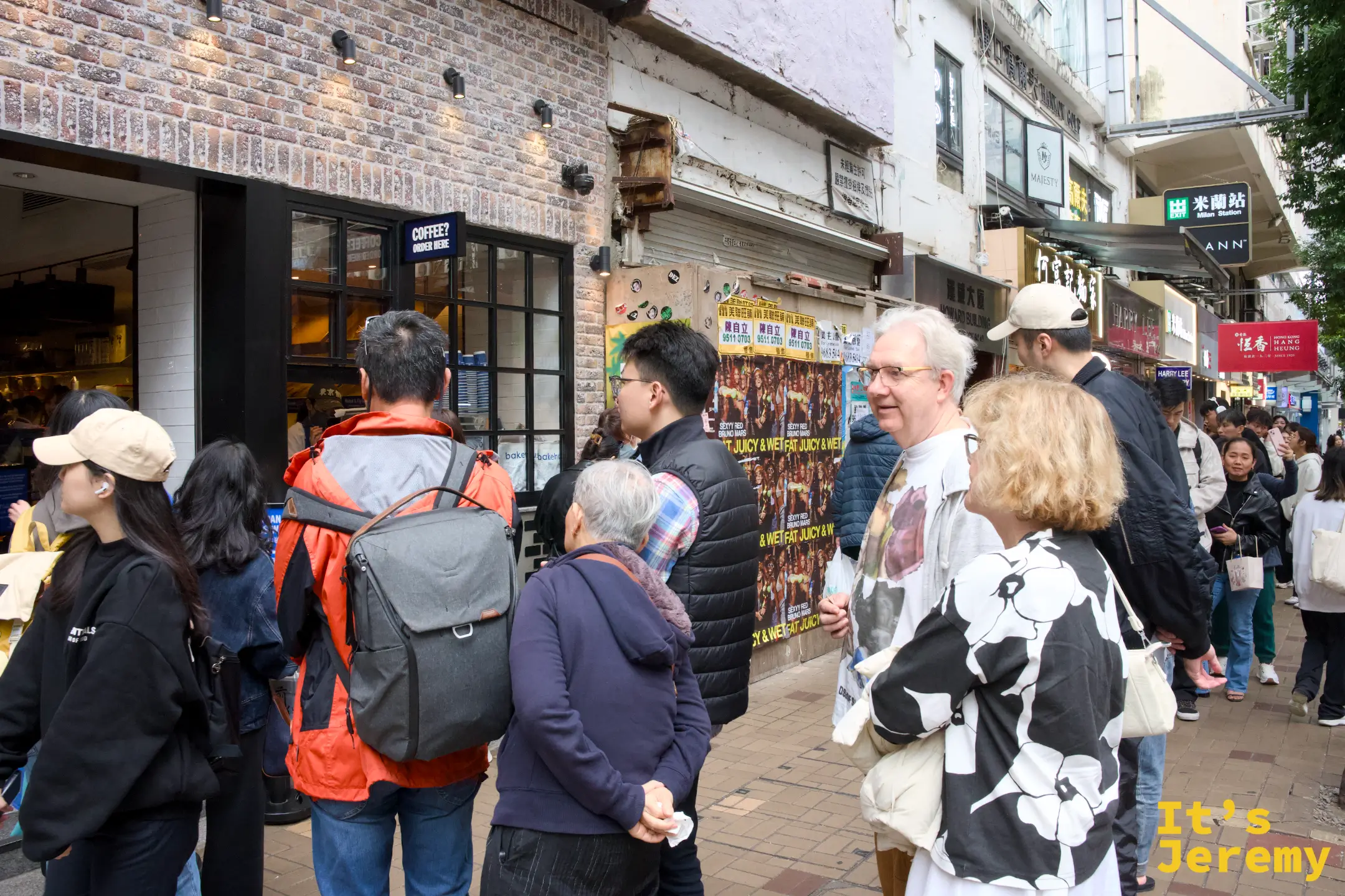 店門口沿街排起的人龍，男女老少都有，磚牆店面外貼著海報