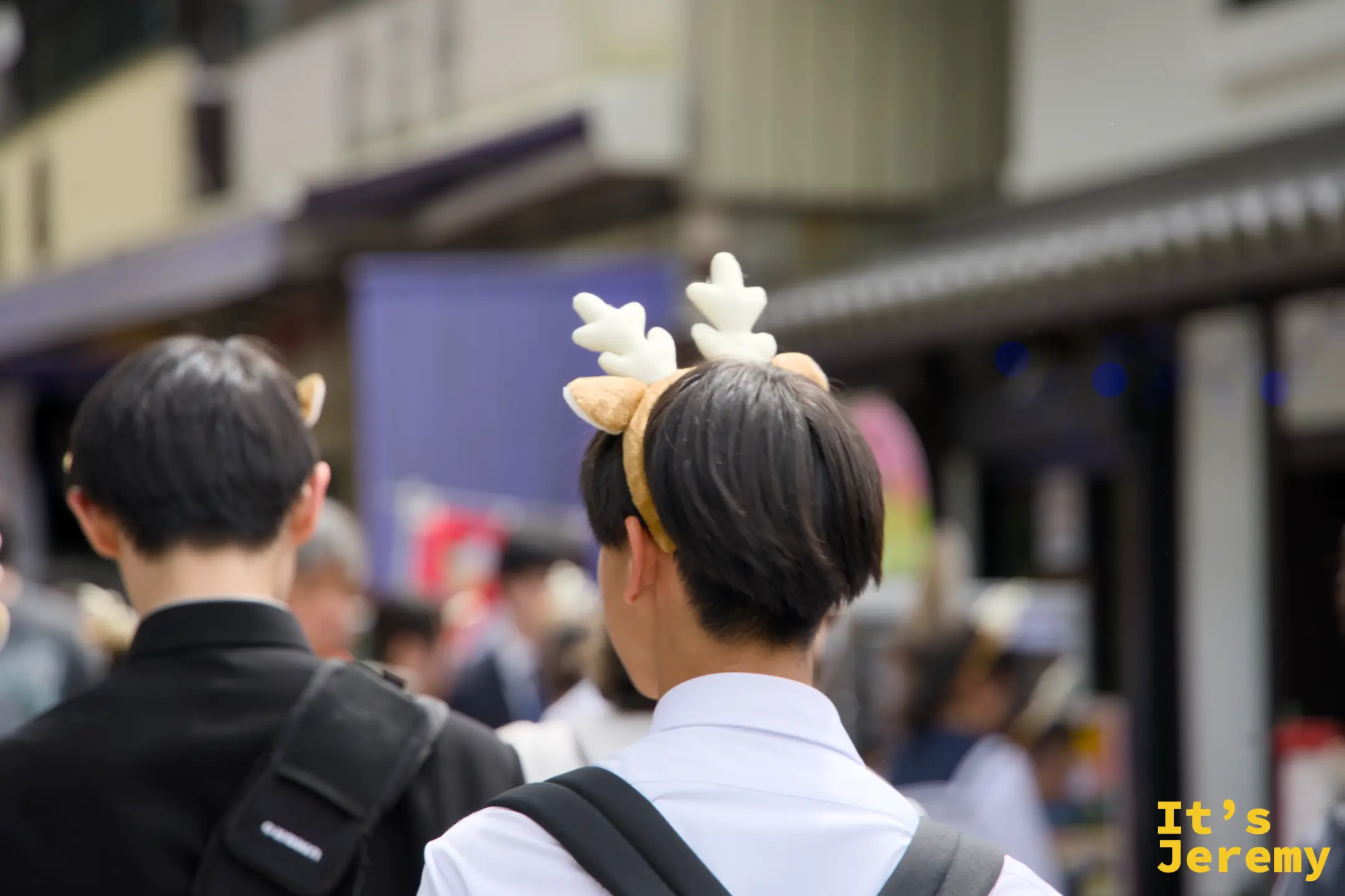 穿制服的學生戴著鹿角造型髮箍走在奈良商店街
