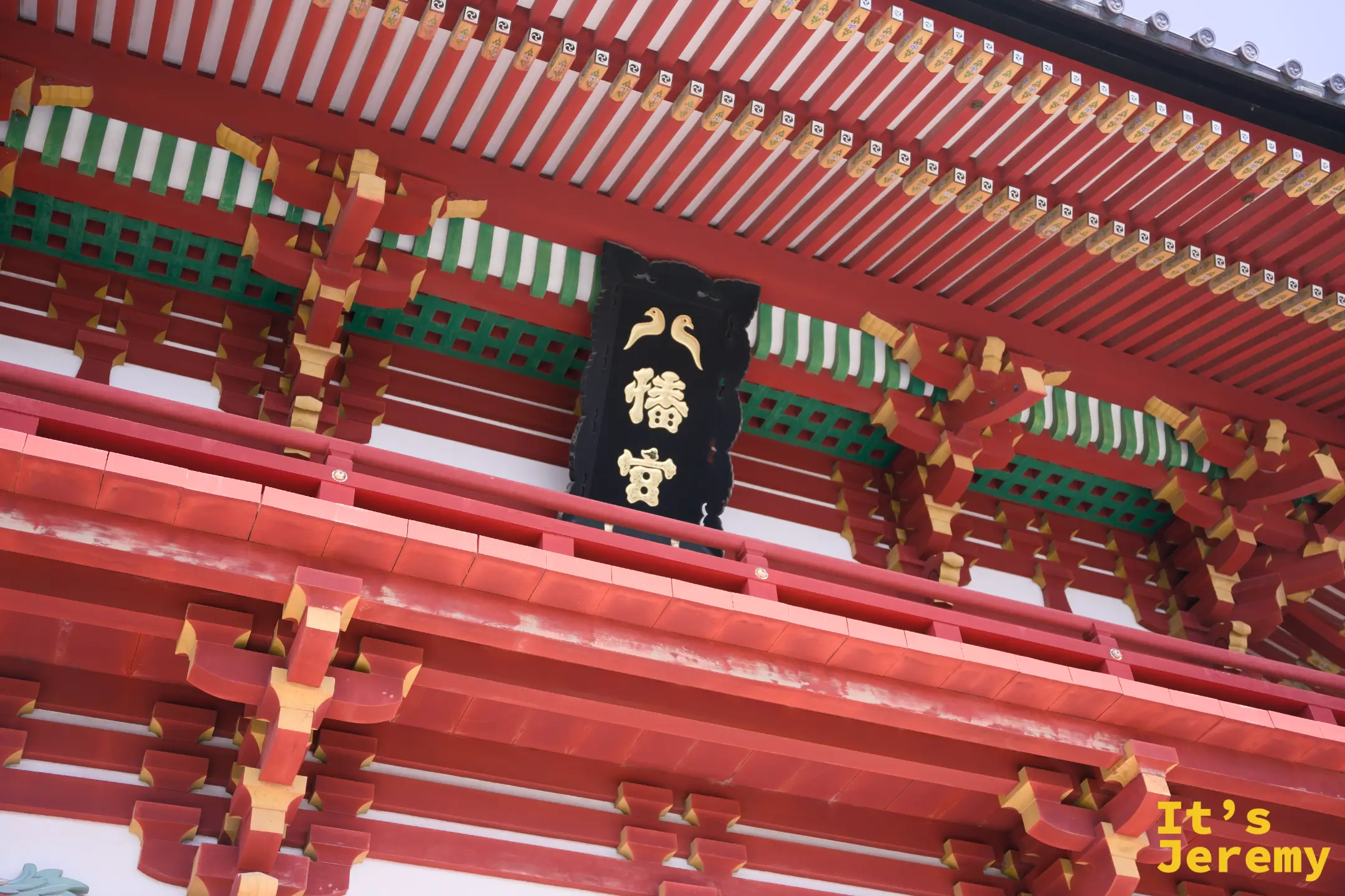 樓門扁額近拍，黑底金字「八幡宮」懸掛於朱紅構件之間