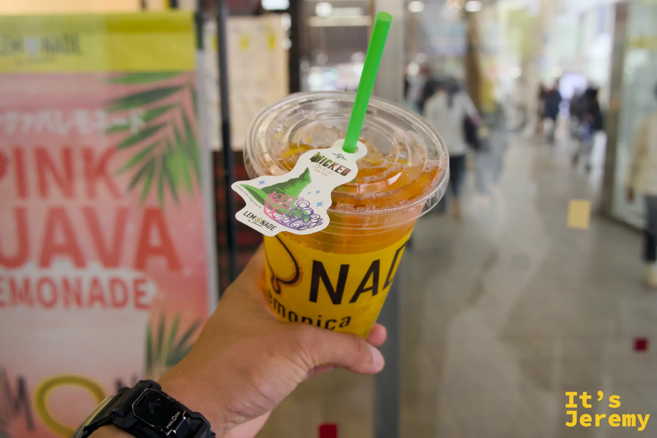 手持 LEMONADE Wicked 聯名飲品，橙黃色飲料