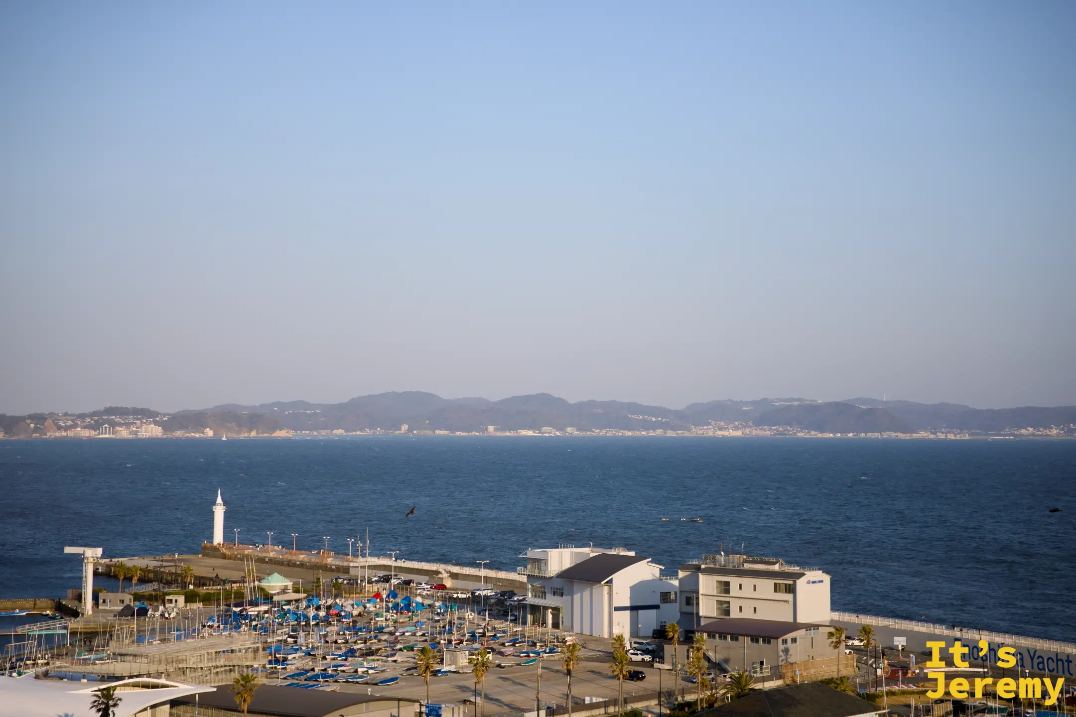 另一角度的展望台視野，前景可見 Enoshima Yacht Harbor 建築與白色燈塔