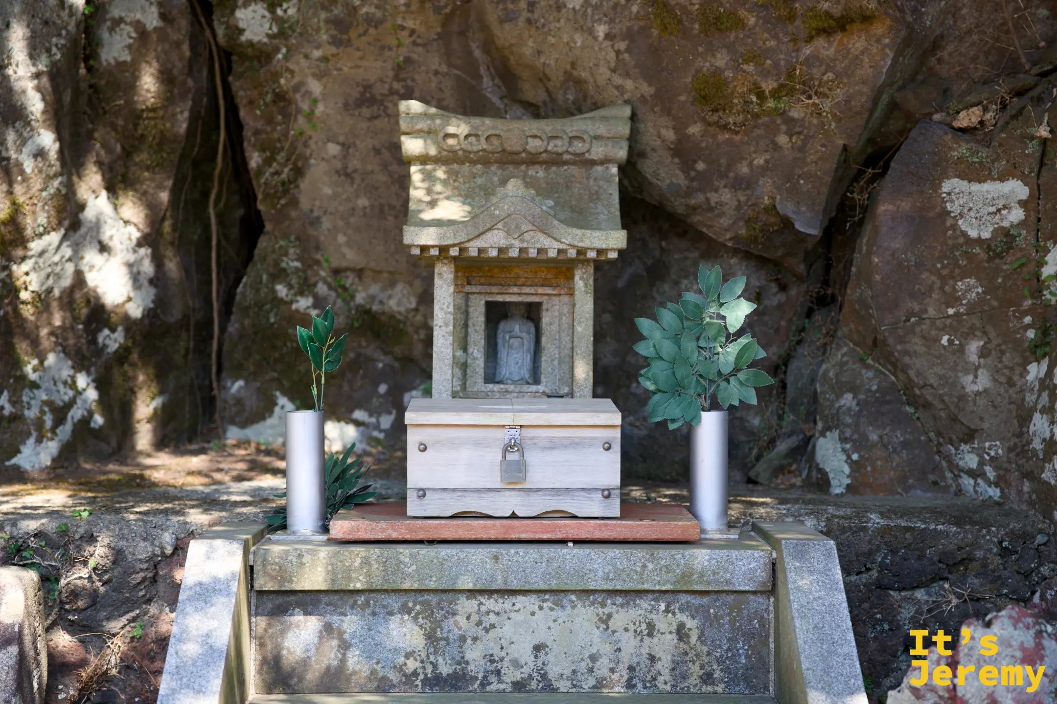 岩石壁龕中的小型石祠，內置佛像，兩側擺有植物裝飾