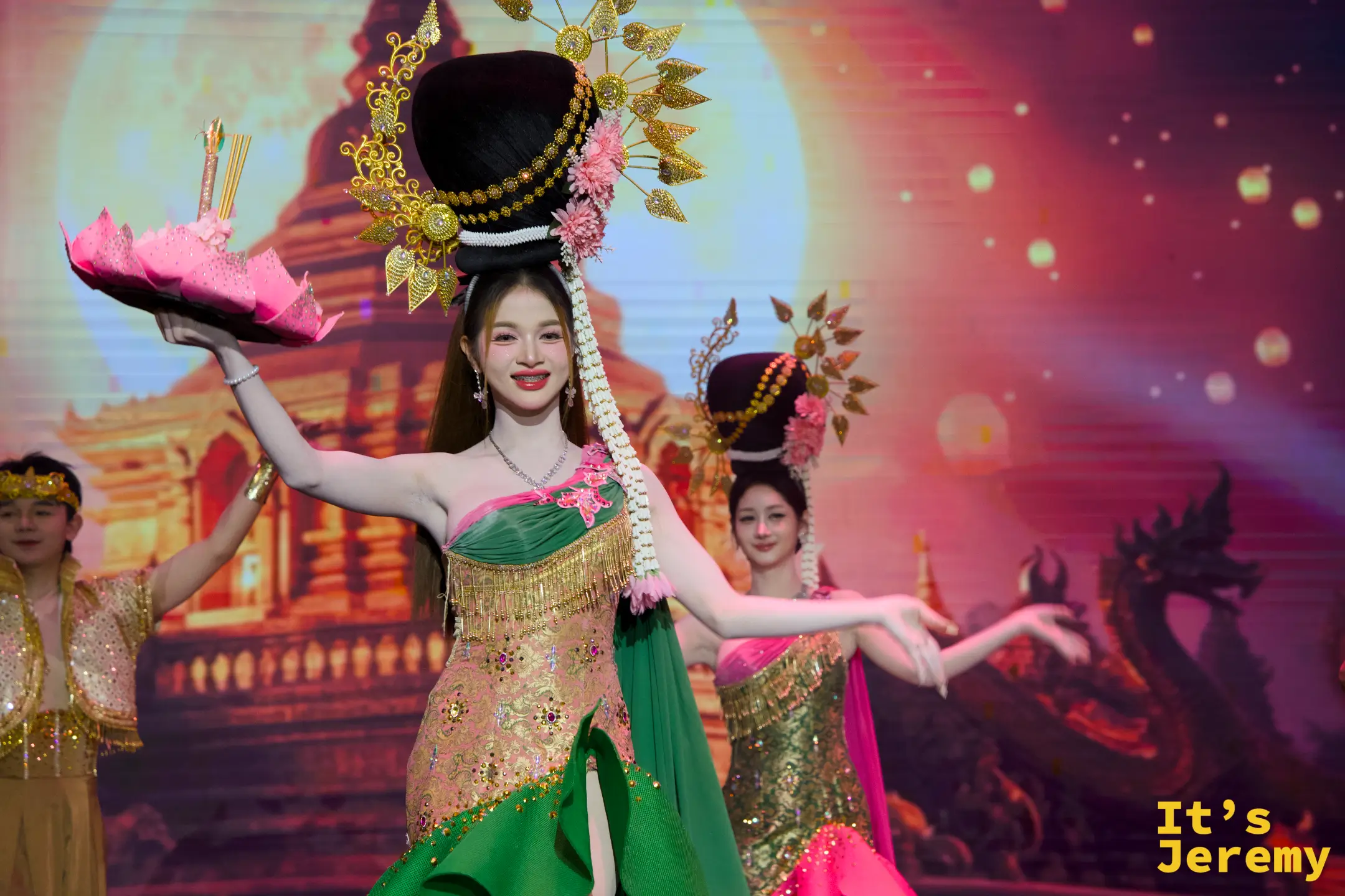 金東尼人妖秀舞台上，舞者身穿綠粉相間的傳統泰服，高戴精緻金色髮飾，手托粉色水燈模擬水燈節慶典。