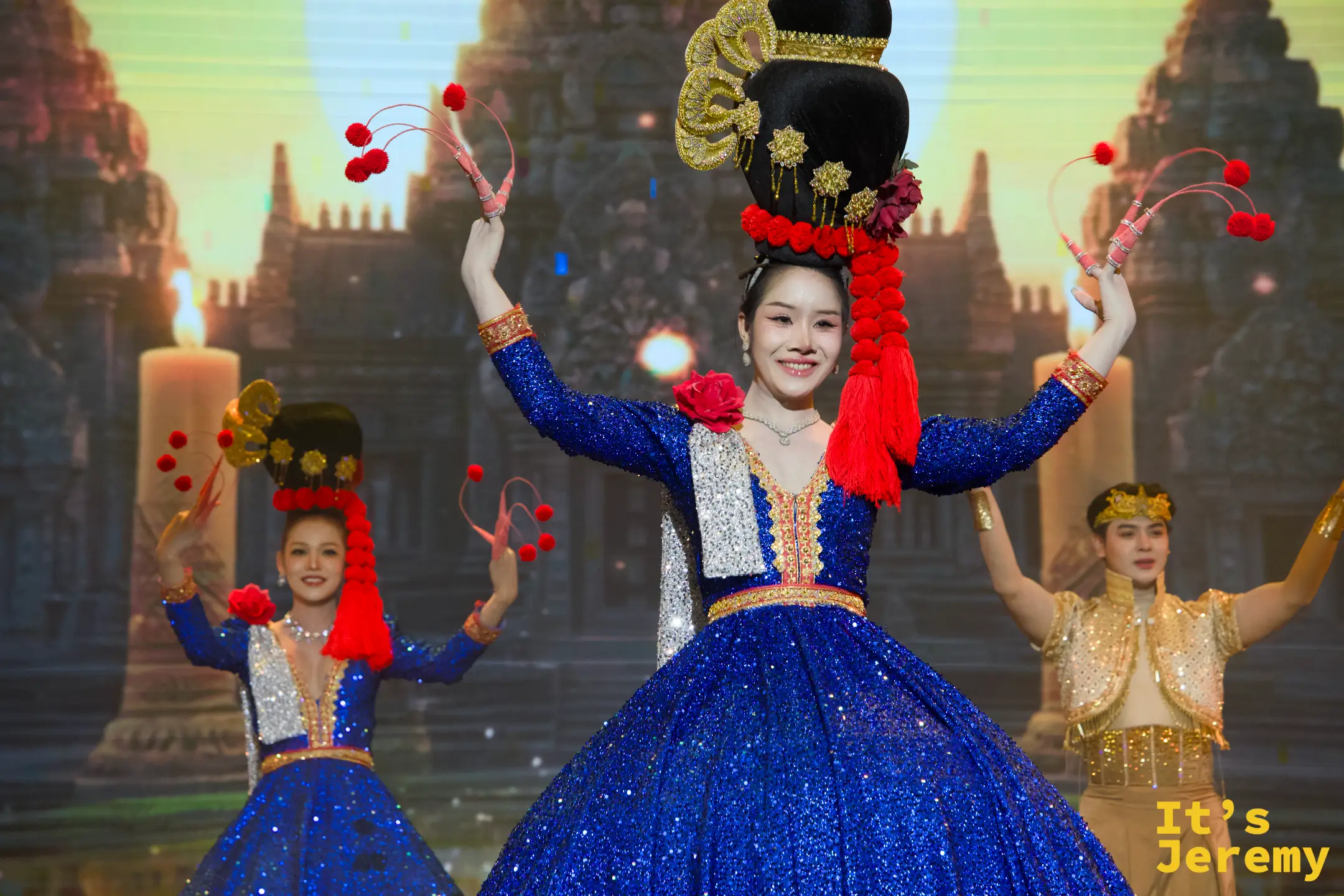 泰國金東尼人妖秀（Golden Dome Cabaret Show）舞台上，舞者們身穿華麗的藍色與金色亮片禮服，頭戴誇張的精緻髮飾進行舞蹈表演。