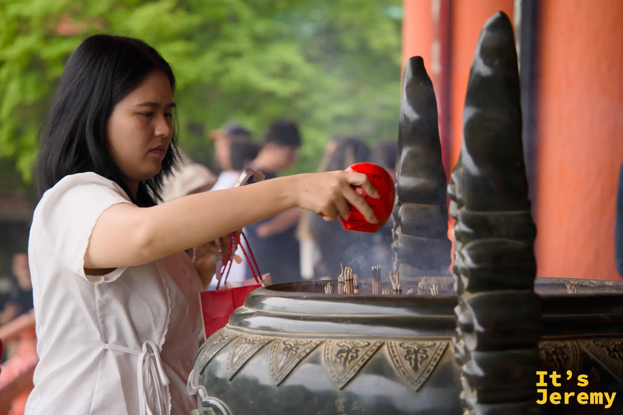 女性拿著小達摩靠近香爐，讓煙霧繚繞達摩