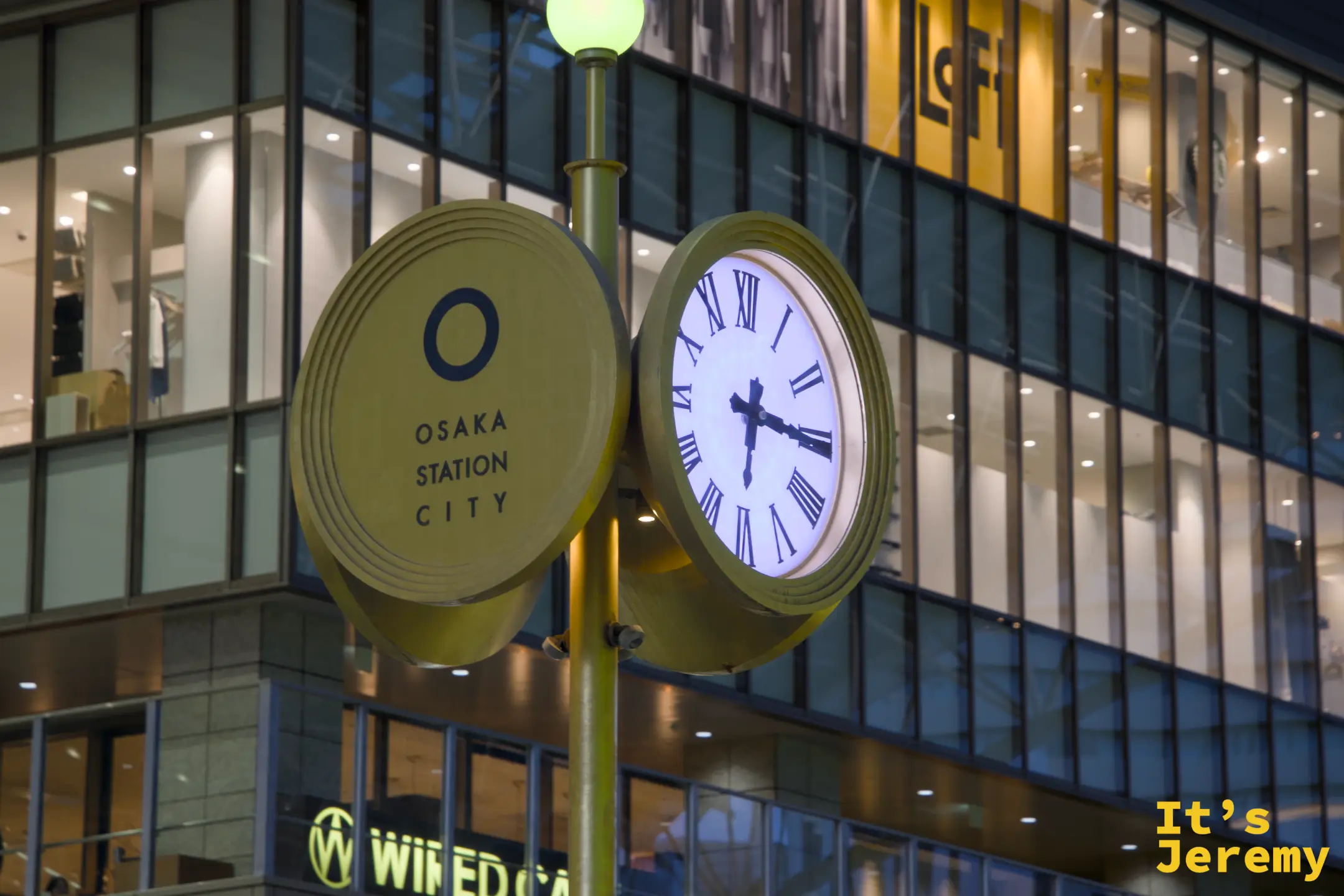 Osaka Station City 圓形時鐘路燈，入夜亮起，背後是 Loft 的玻璃帷幕，這一帶是梅田逛街最標誌性的地標之一