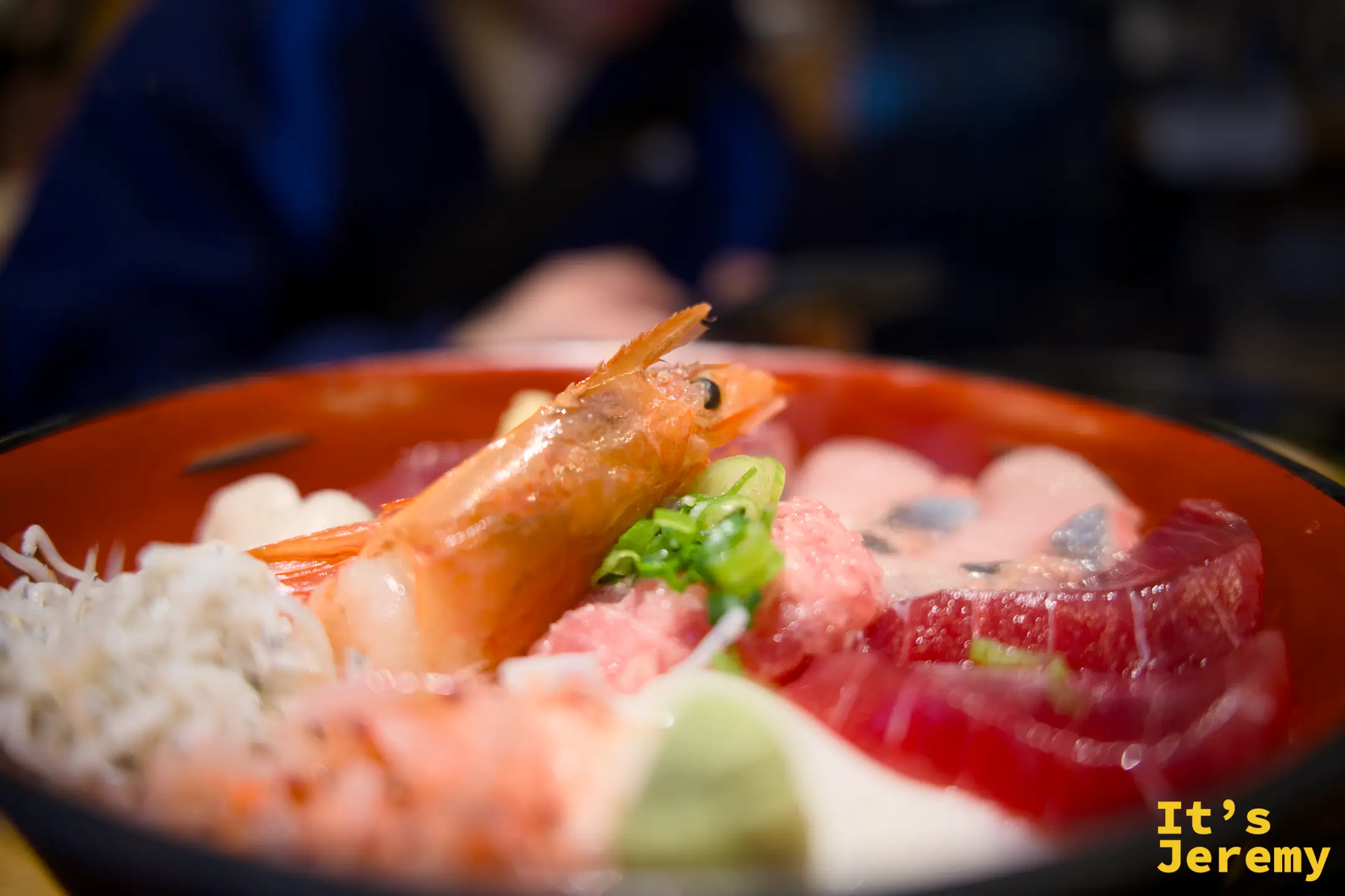 丸天丼近景，整隻大蝦天婦羅和鮮蝦疊在醋飯上