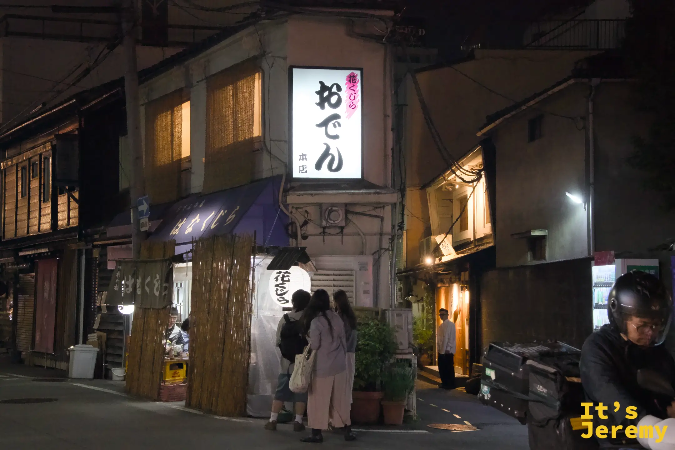 花くじら 本店外觀，入夜後おでん燈箱亮起，旁邊是竹籬笆圍起的等候區