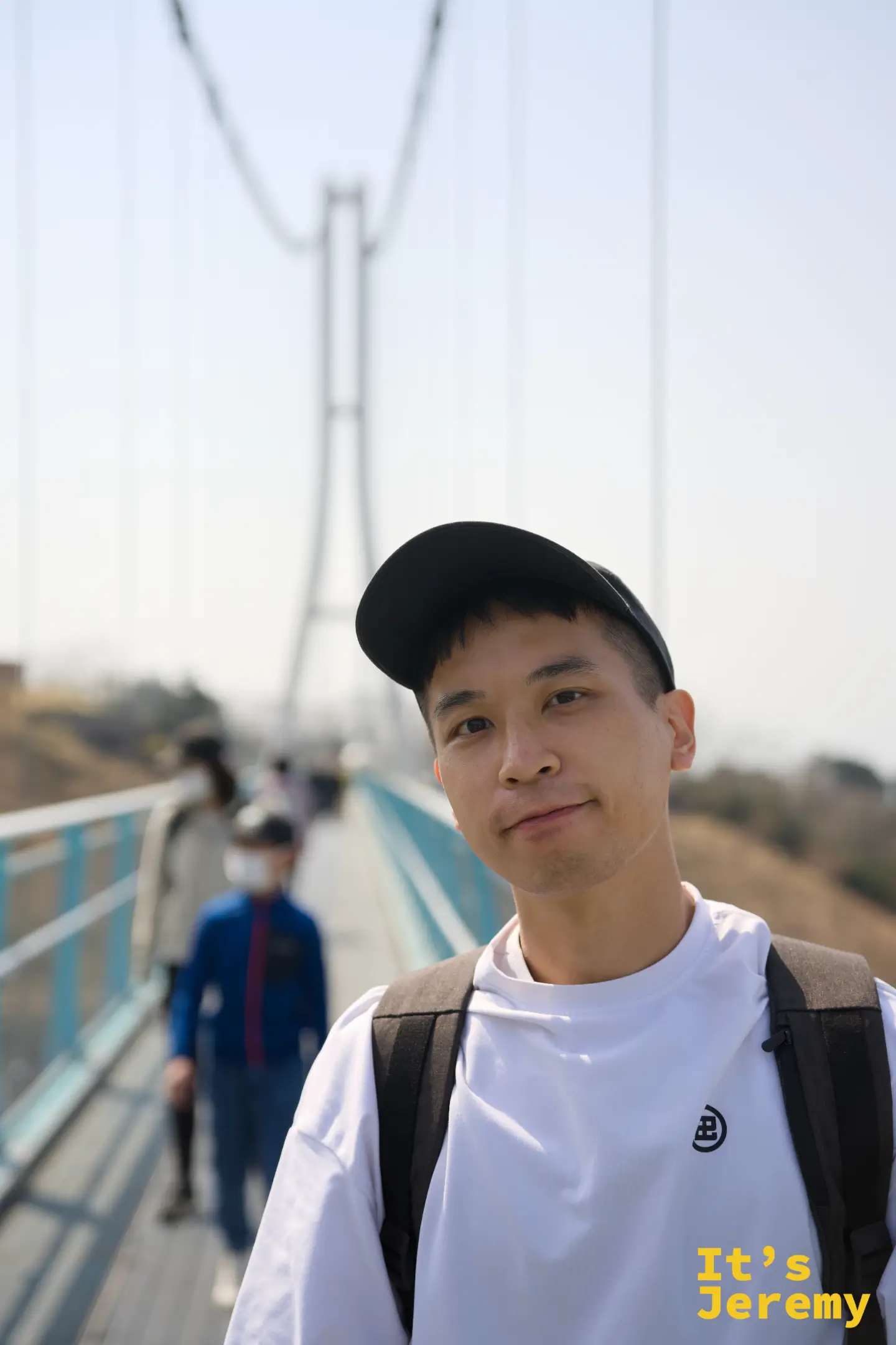 Jeremy 站在橋上，背後是鋼纜與橋塔在晴空中延伸