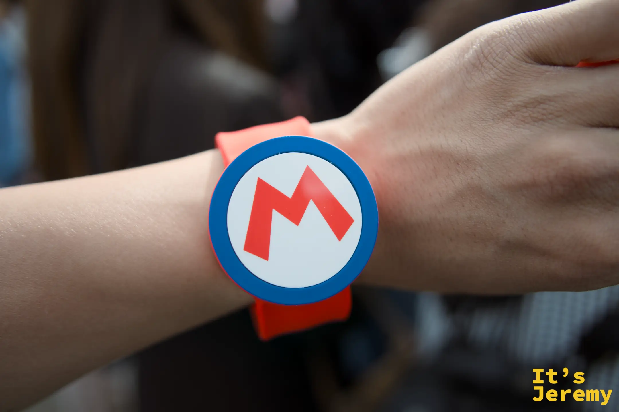 Mario Power-Up Band 手環，圓形設計搭配 M 字 LOGO，橘色腕帶非常顯眼