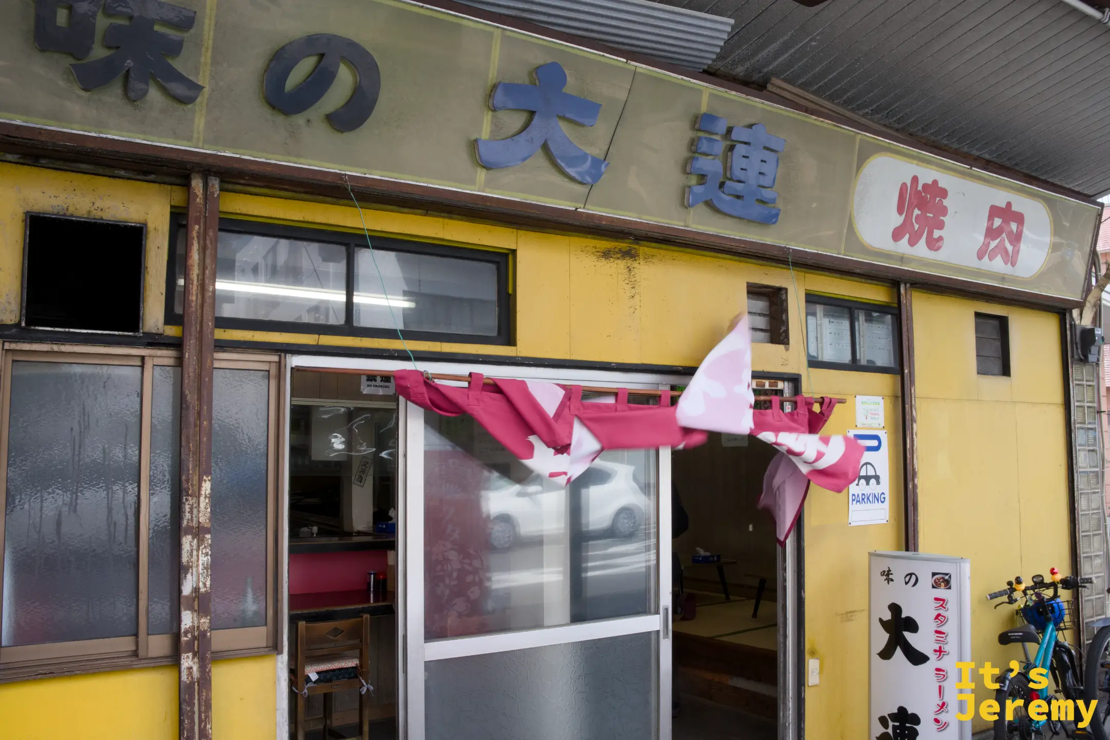 味の大連招牌近景，藍色文字招牌與店前紅白旗幡