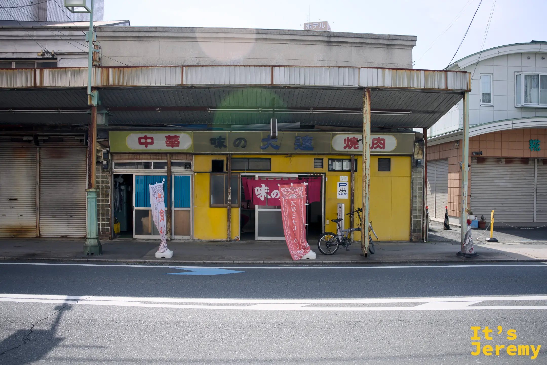 中華味の大連全棟正面外觀，黃色外牆配紅色暖簾與白色旗幡