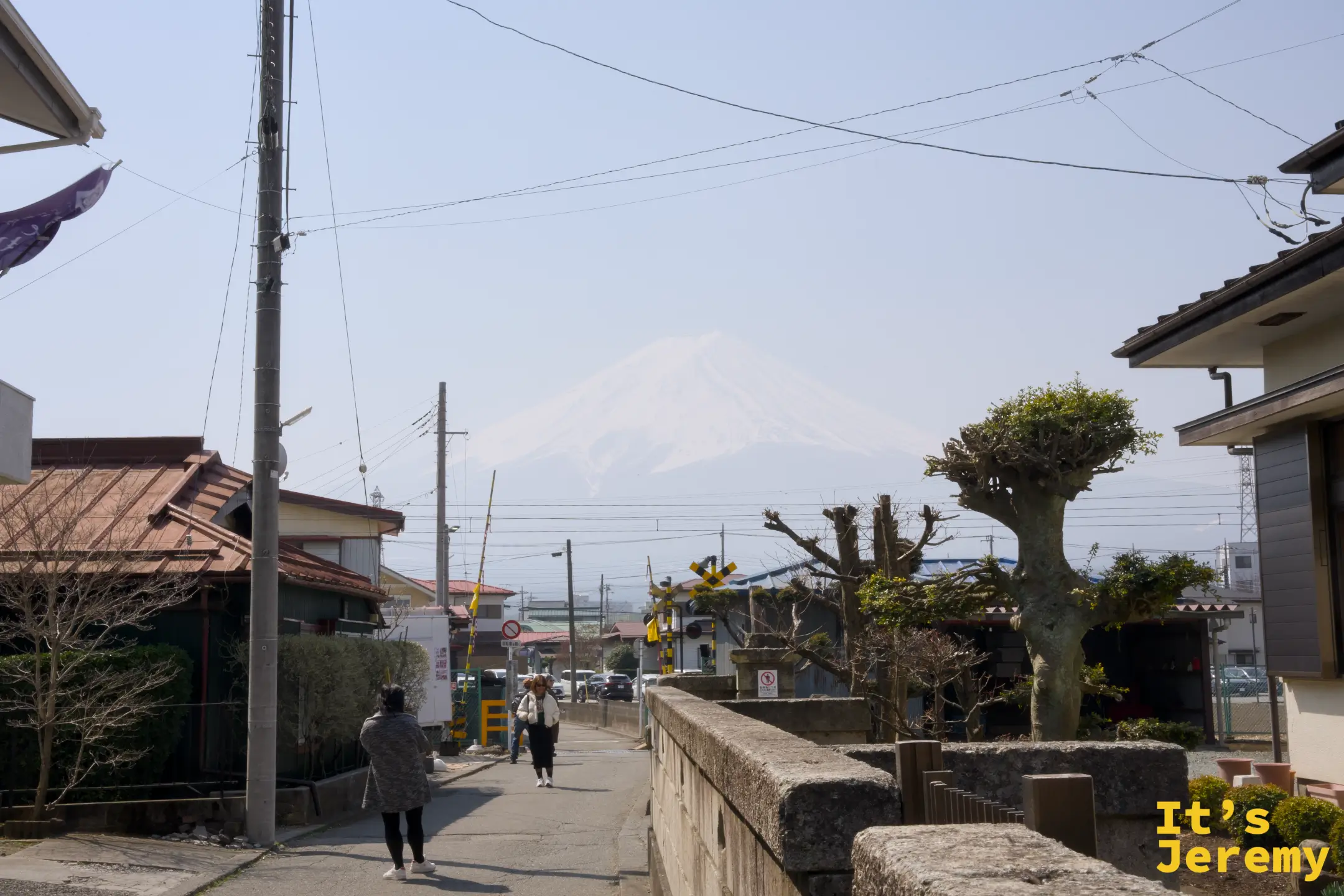下吉田住宅區的巷子，富士山從房屋與電線桿的縫隙間現身，山體被沙塵染成紙白色