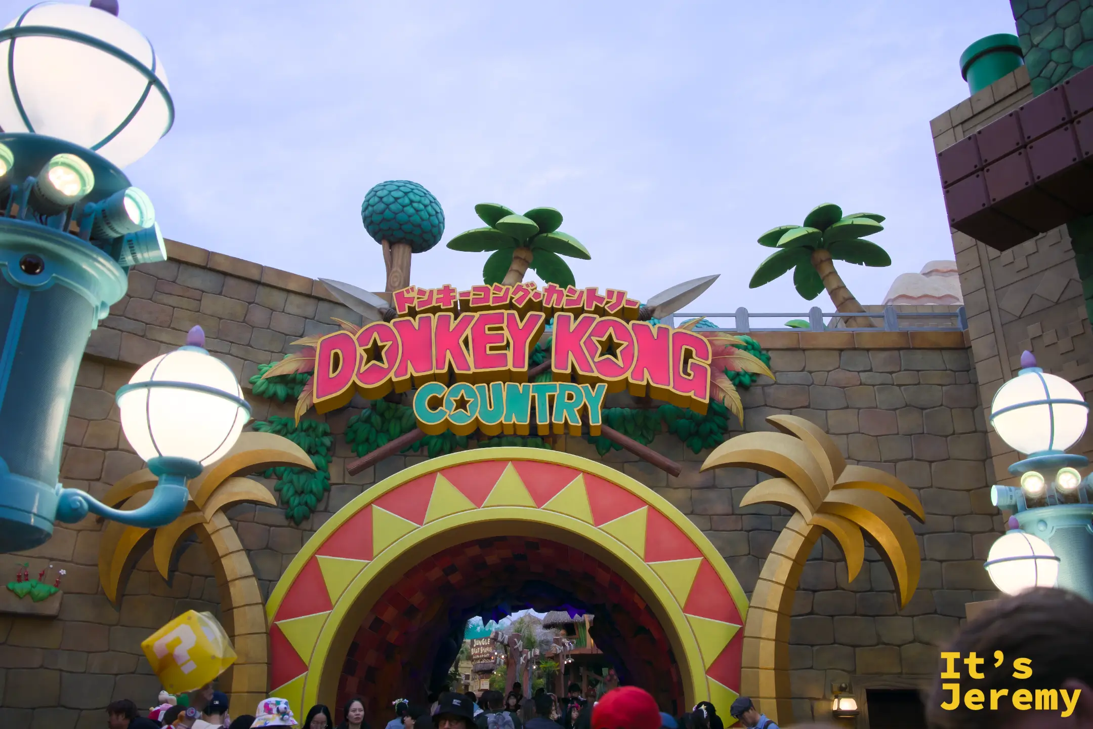 Donkey Kong Country 的入口拱門，招牌以紅色粗體字呈現，兩側是可可椰子樹造型裝飾