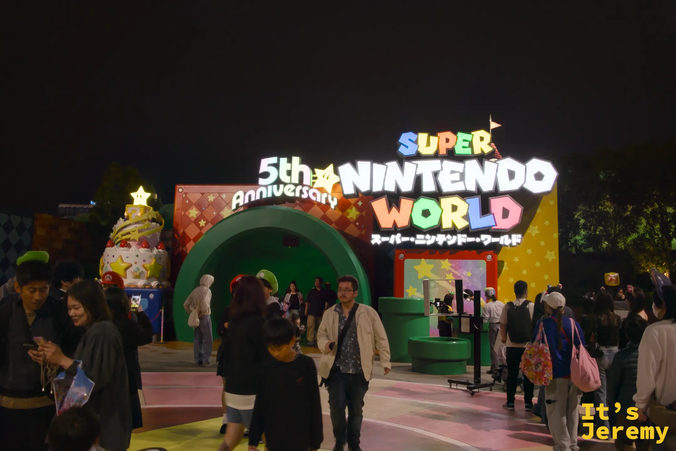 入夜後的超級任天堂世界入口，5th Anniversary 標誌與 Super Nintendo World 的彩色字體在黑夜中格外醒目